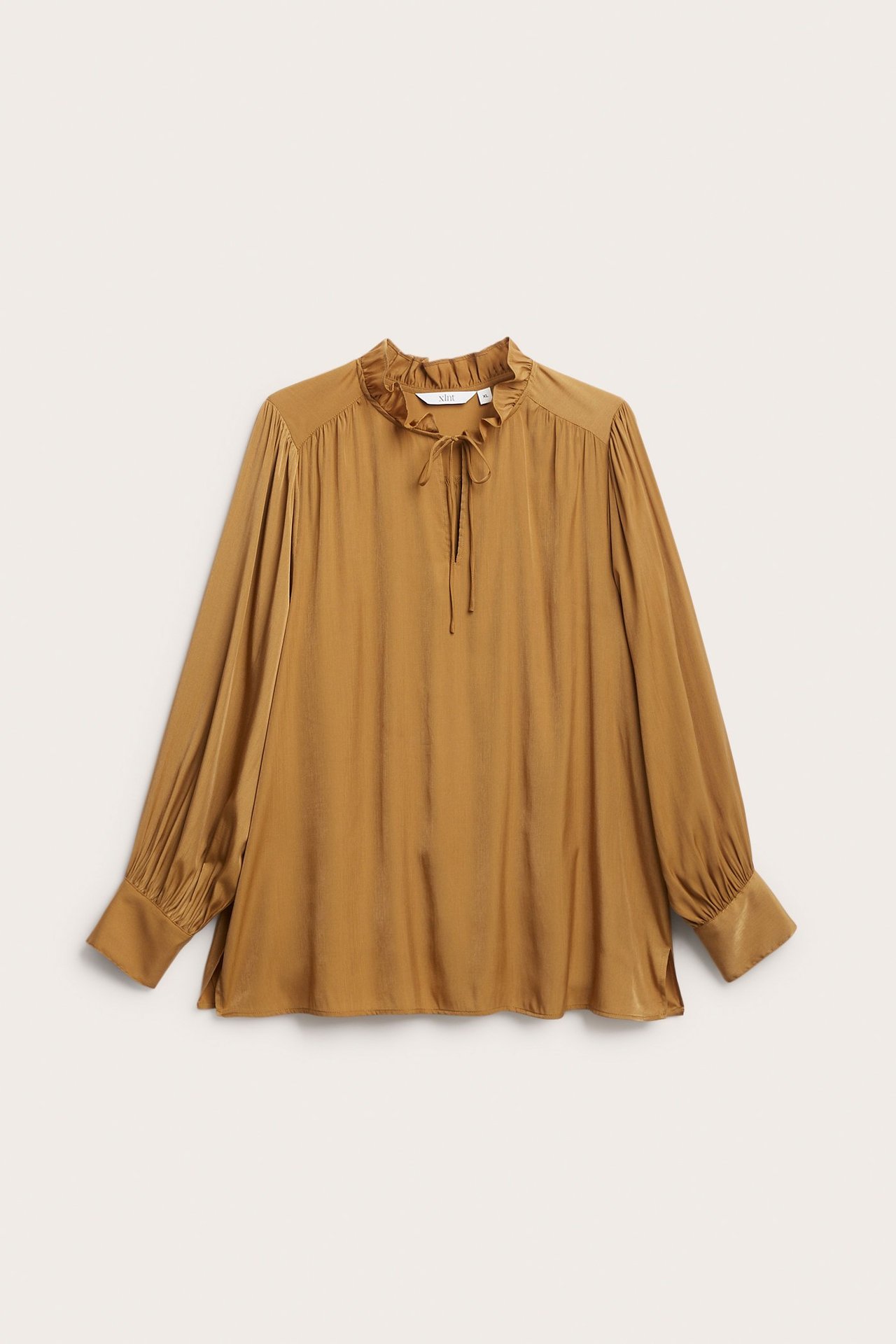 Frontvisning av en beige langermet damebluse med rysjekrage, knyting og rynkede mansjetter.