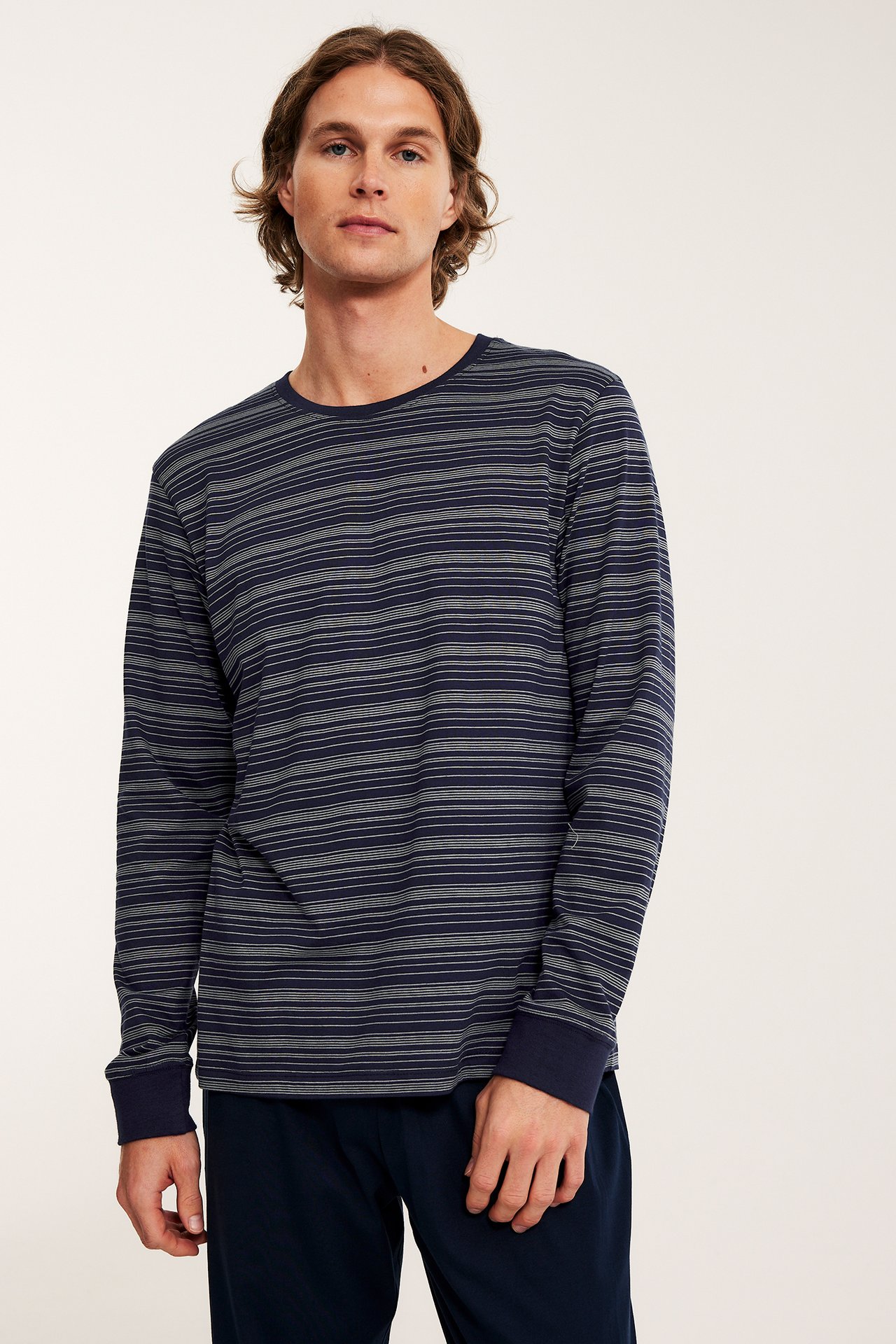 Frontbilde av mann i mørkeblå stripet bomulls-pyjamasoverdel og mørkeblå pyjamasbukser.