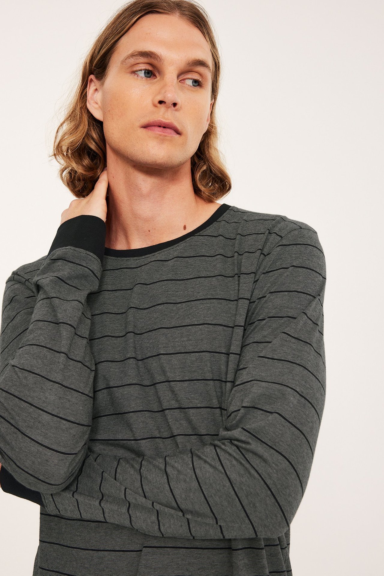 Närbild framifrån: man i en grå pyjamaströja i bomull med svarta ränder, krage och muddar.