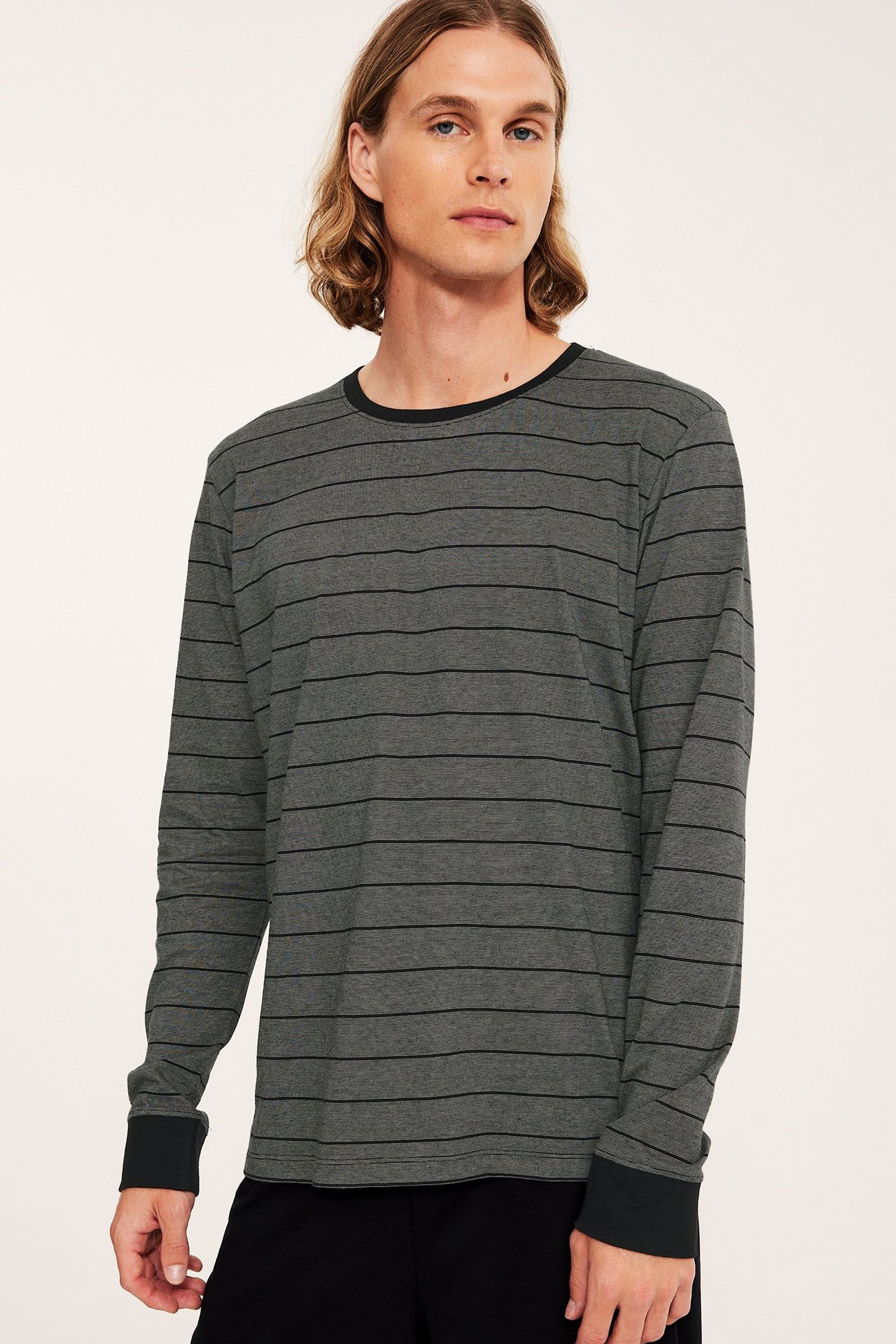 Widok z przodu mężczyzny w szaro-czarnej, pasiastym bawełnianej koszulce piżamowej z czarnymi mankietami.