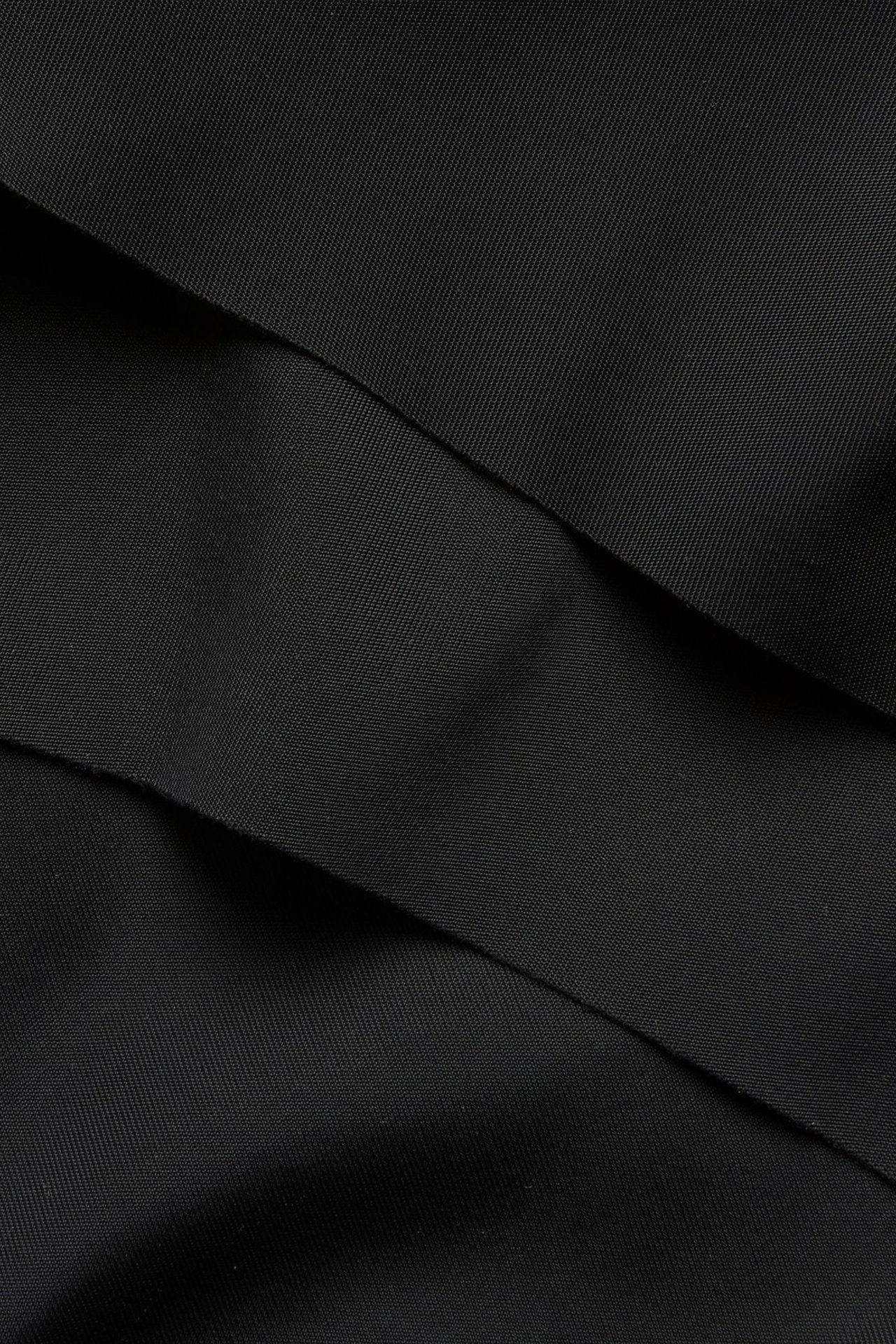 Nærbilde av svart polyamid- og elastanstoff med glatt, tøyelig tekstur.