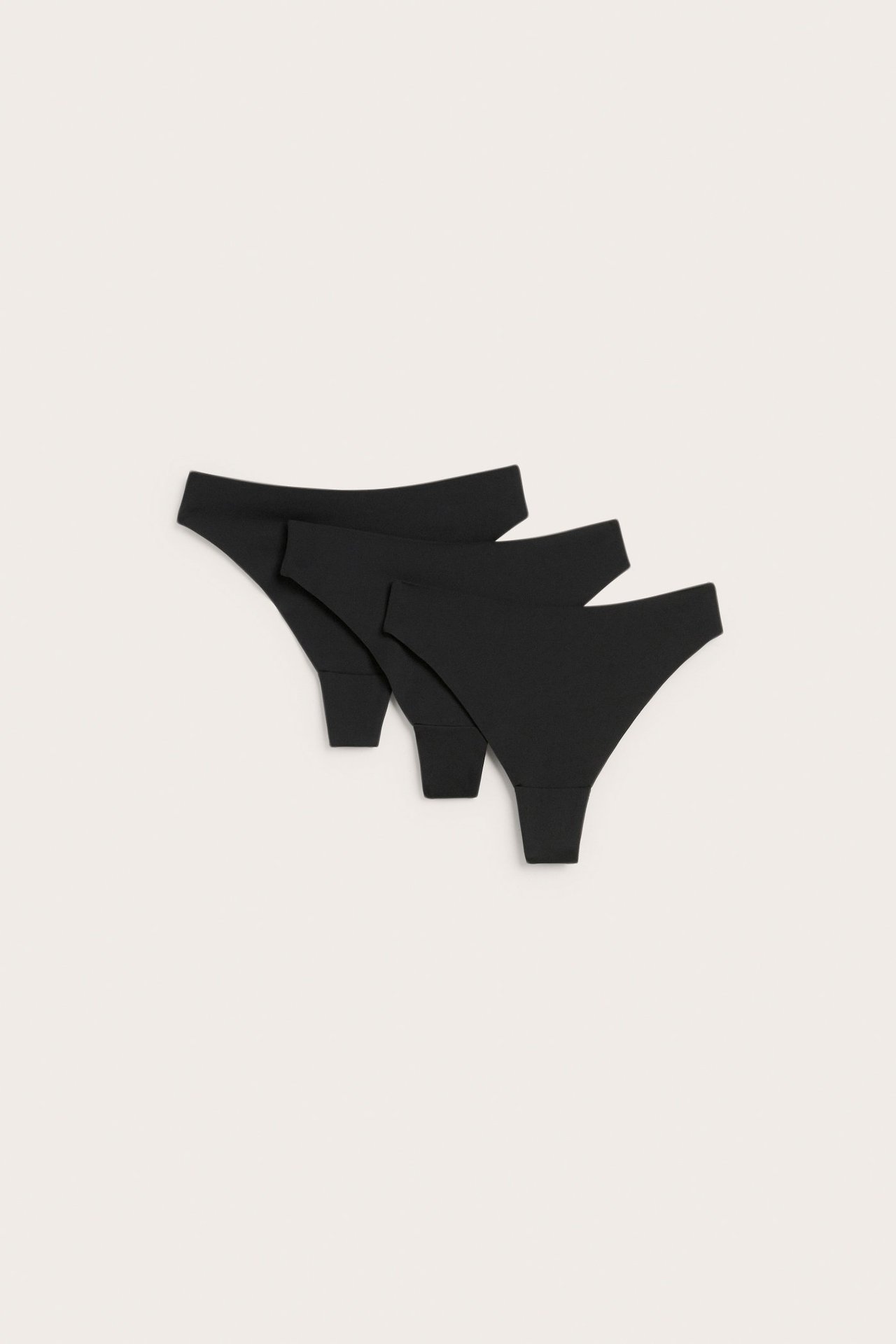 Topputsikt av tre svarte clean cut stringtruser laget av stretchy mikrostoff.