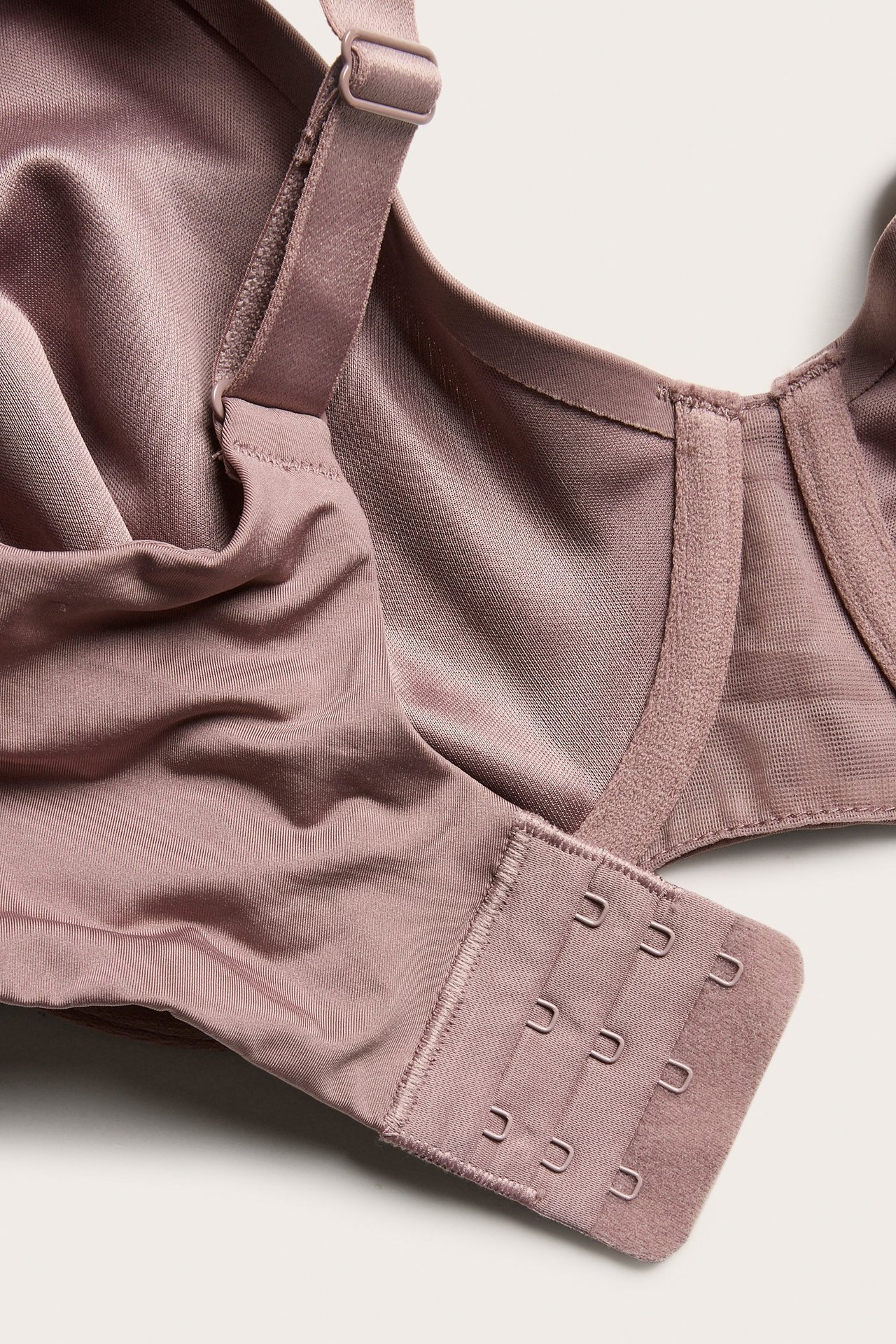 Zbliżenie na ciemnoróżowy, nieusztywniany biustonosz minimizer z szerokimi ramiączkami i zapięciem na haftki.