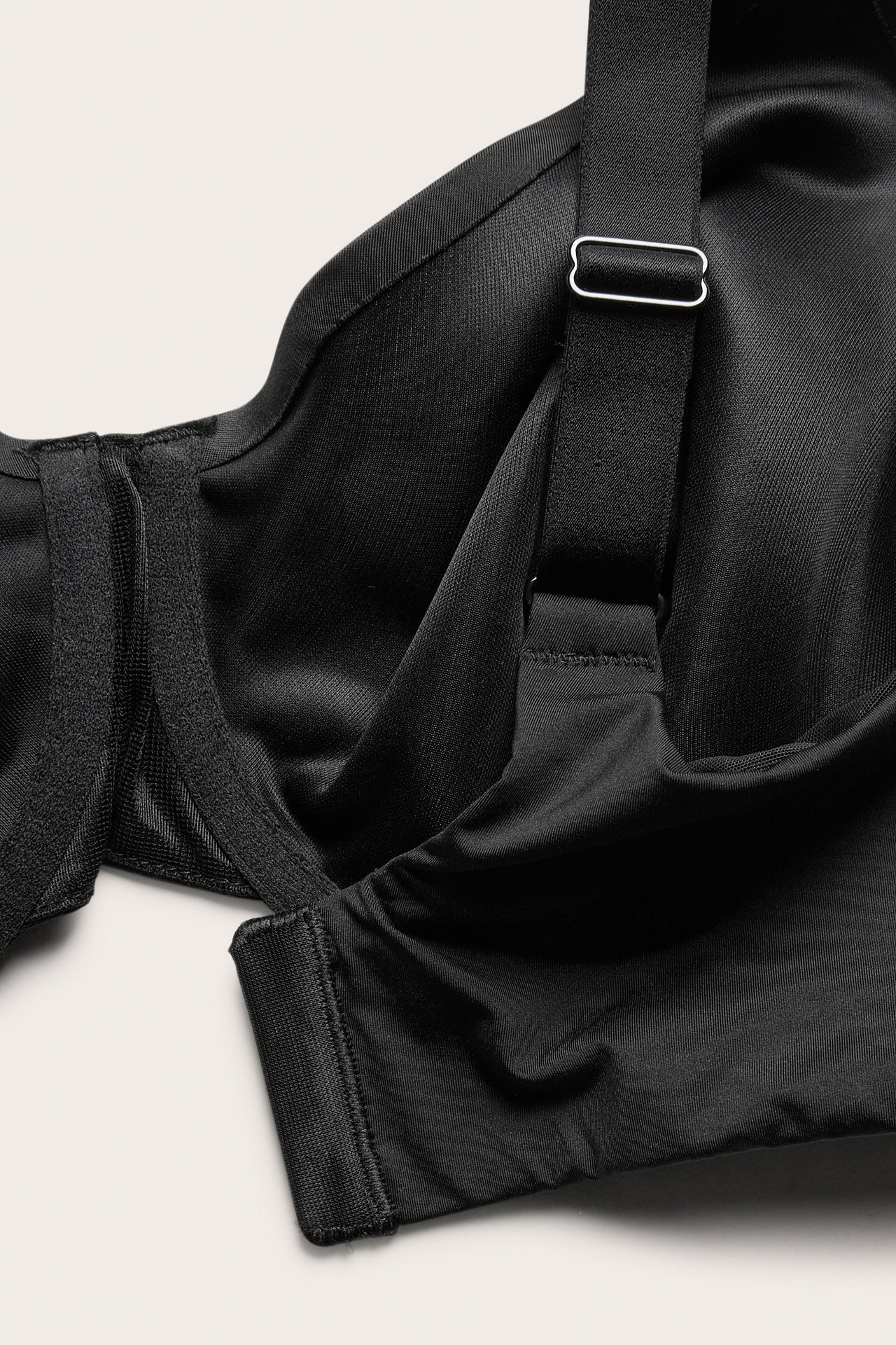 Zbliżenie czarnego, niewyściełanego biustonosza typu minimizer z szerokim, regulowanym ramiączkiem.