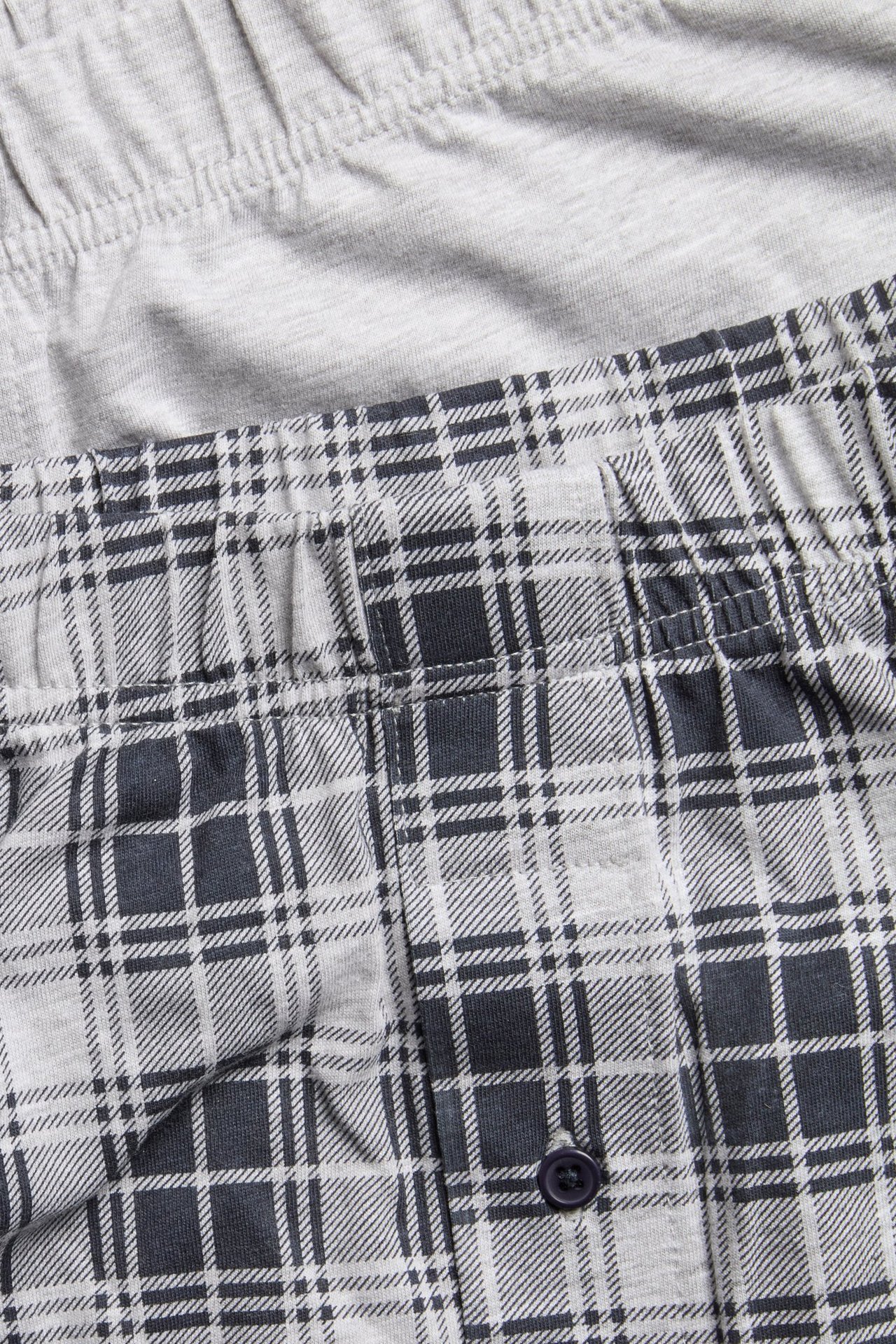 Nærbilde av rutete lysegrå herretruser med knappelukking, og ensfargede lysegrå truser.