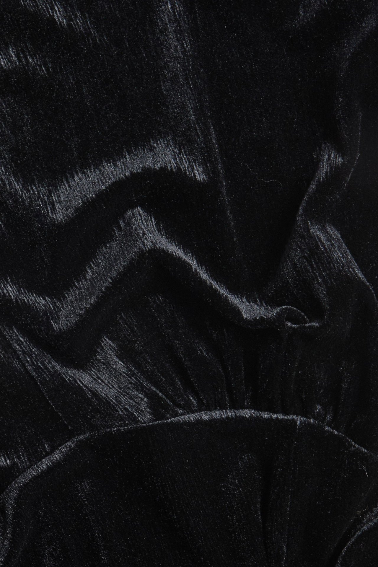 Zbliżenie czarnej, jednolitej długiej sukienki welurowej z widocznym stretchem i miękką fakturą.