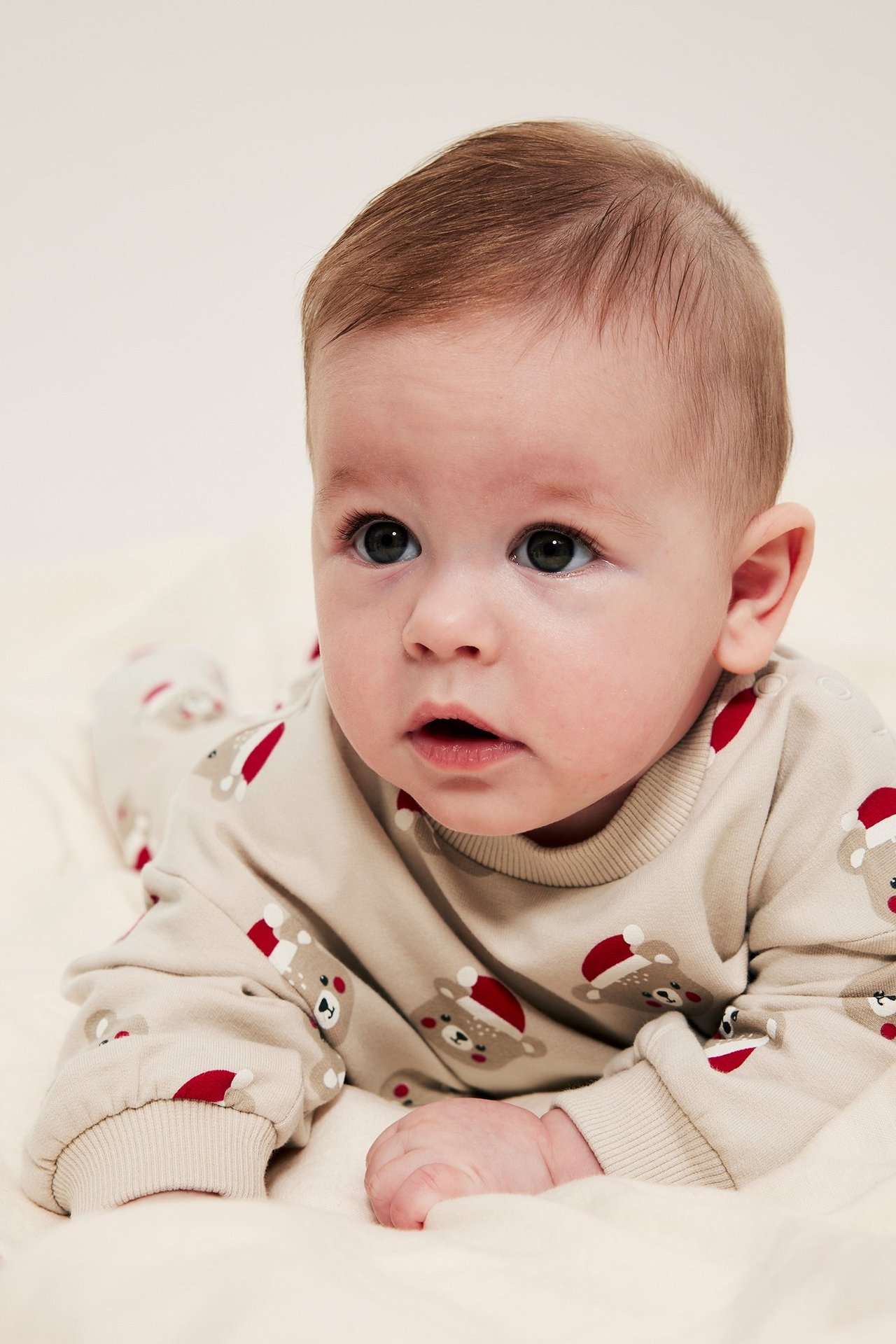 Baby i beige mykset med julMotiv, langermet topp og leggings i fleece.