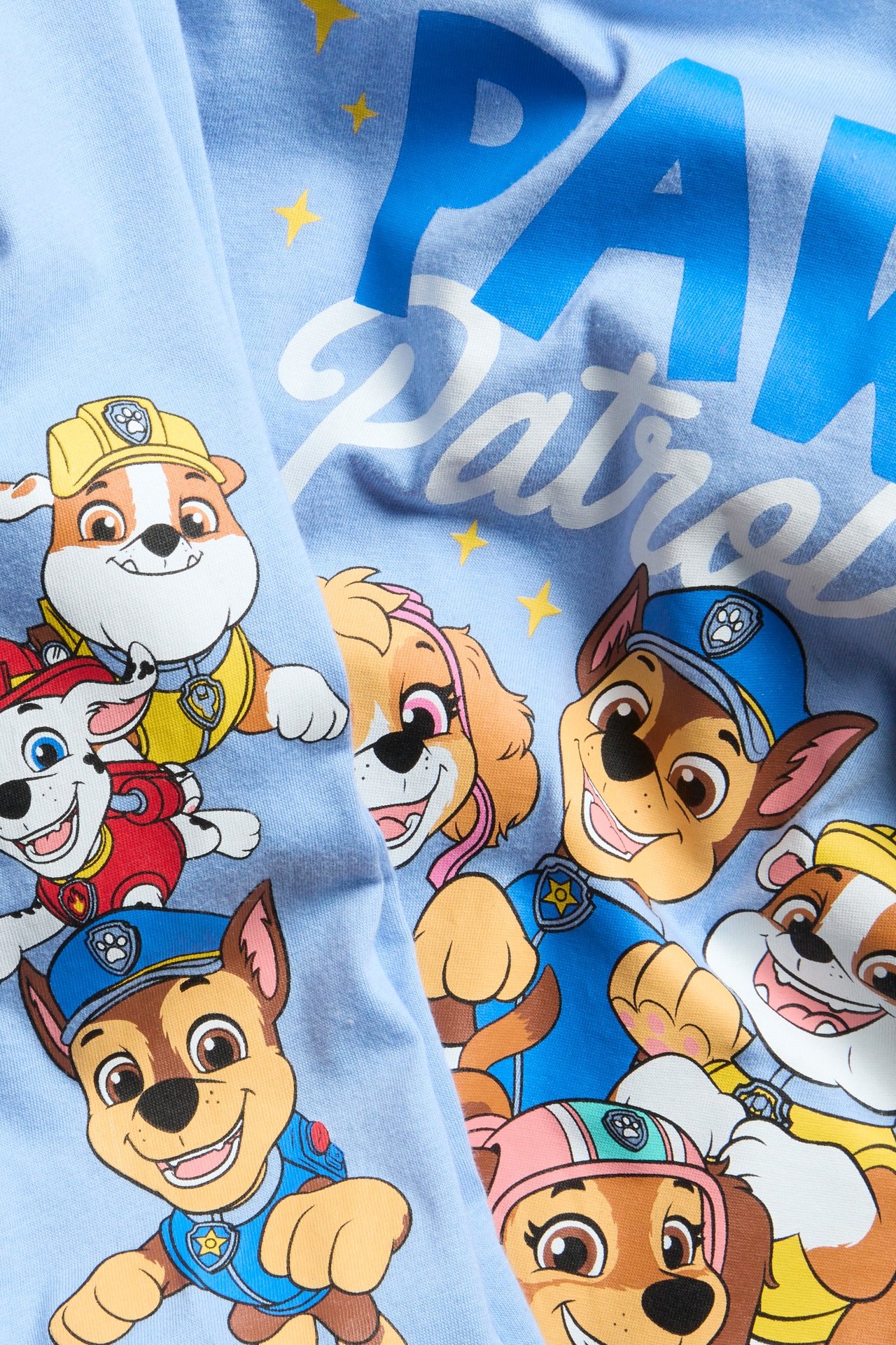 Vaaleansininen pitkähihaiset pyjamat Paw Patrol -kuvalla ja painatuksella yläosassa ja housuissa.