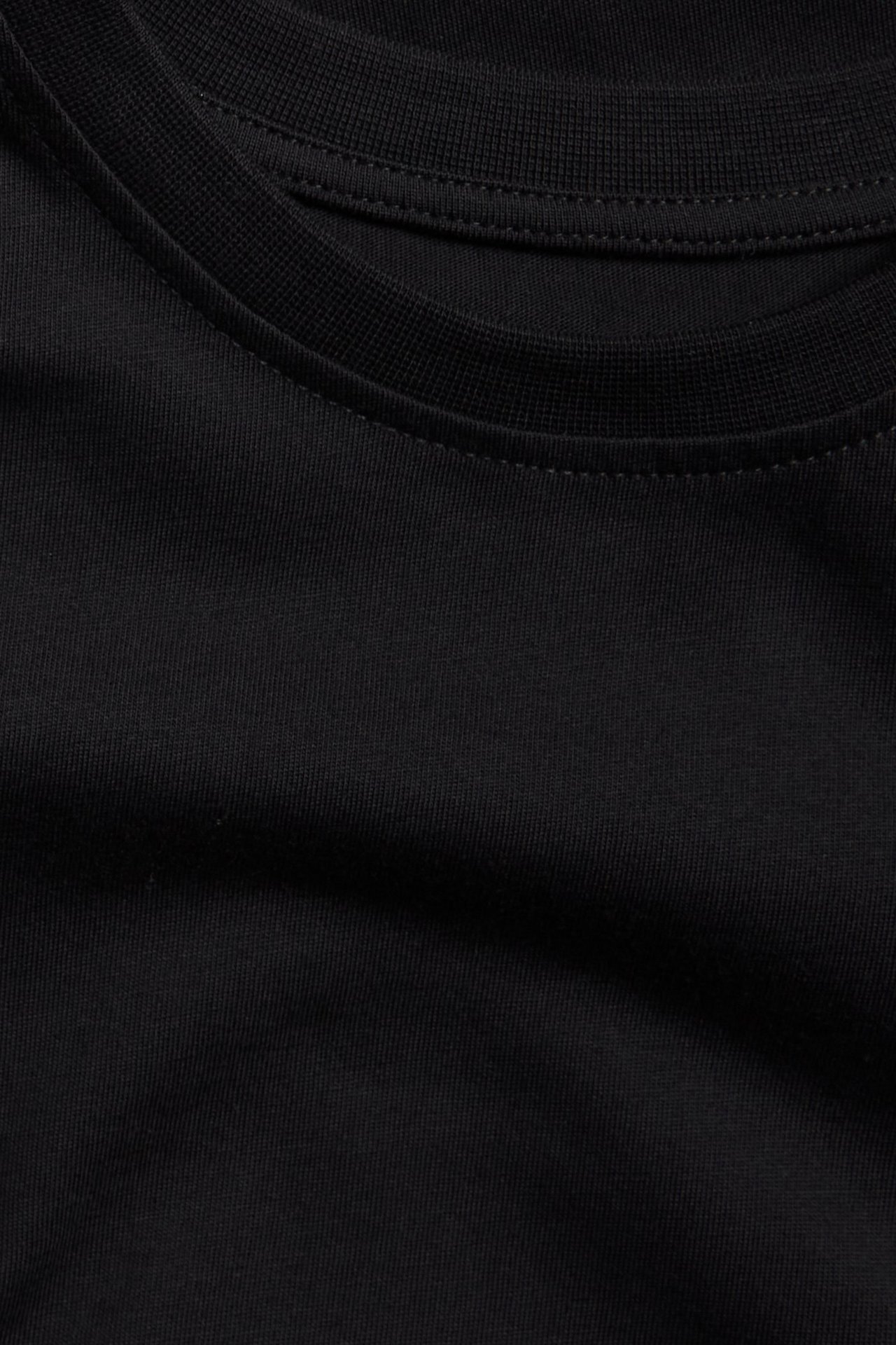 Zbliżenie na gładki czarny bawełniany T-shirt z prążkowanym dekoltem.