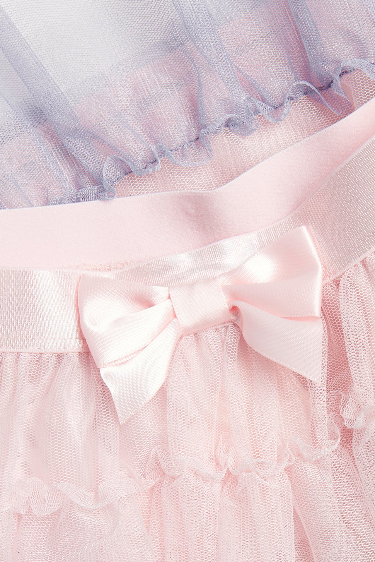 Zbliżenie na różową tiulową spódnicę dziecięcą z falbankami, satynową kokardą, z fioletowym tiulem.