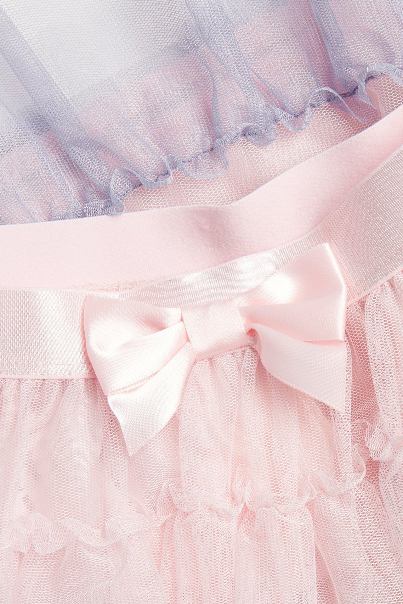 Zbliżenie na różową tiulową spódnicę dziecięcą z falbankami, satynową kokardą, z fioletowym tiulem.