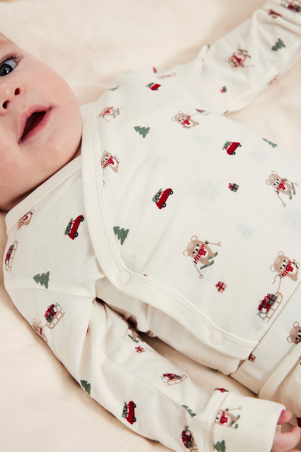 Kremfarget langermet body med julemotiv, knapper på skuldrene, overlap-funksjon.
