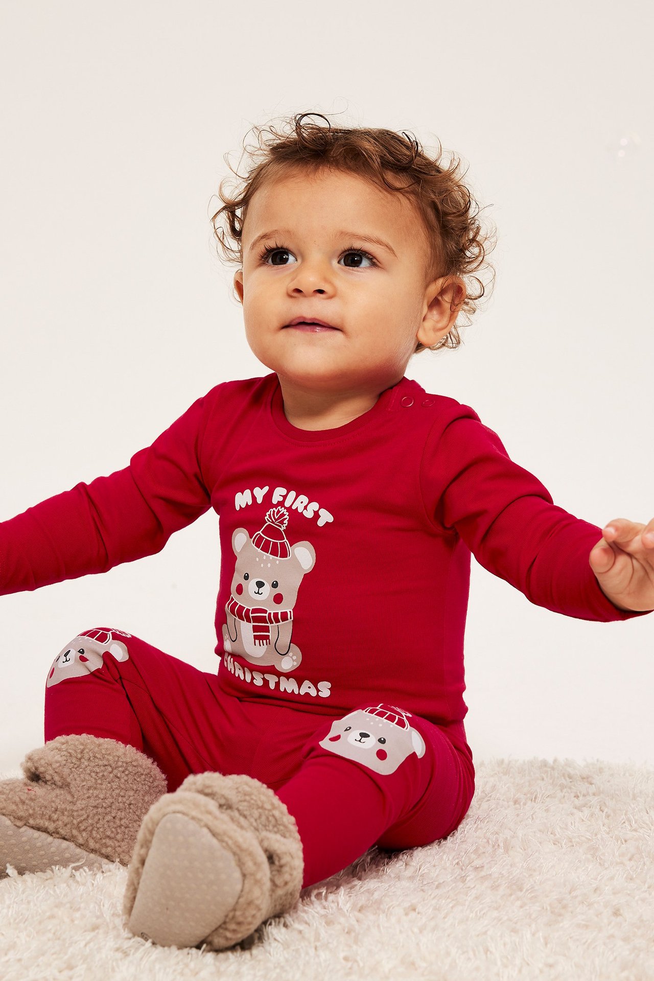 Röd långärmad babybody med julmotiv av en björn med mössa och halsduk, tryck fram.