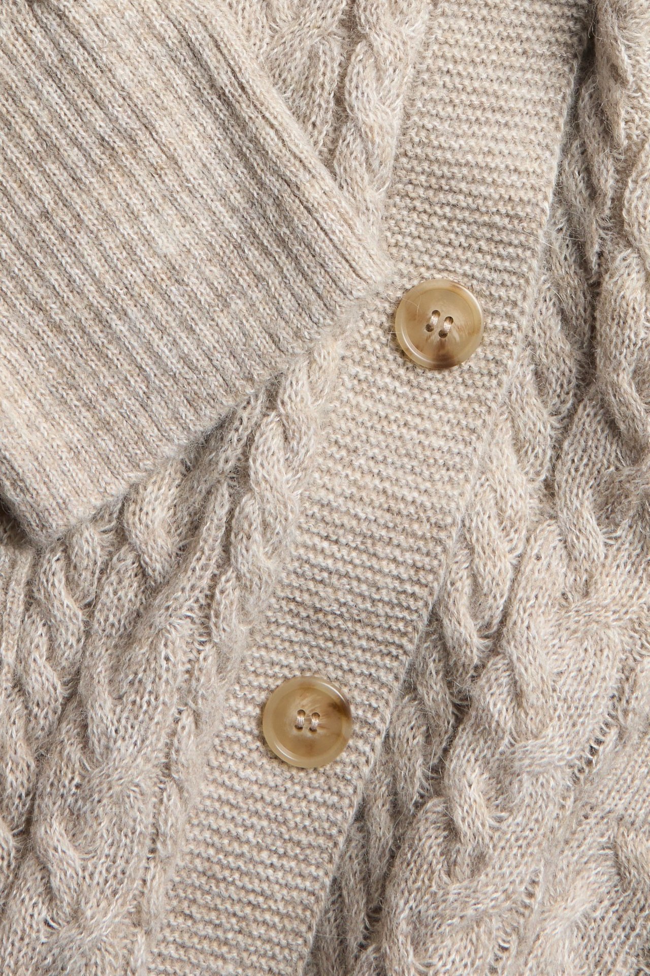 Zbliżenie beżowego melanżowego kardiganu w warkocze z dwoma jasnobrązowymi guzikami.