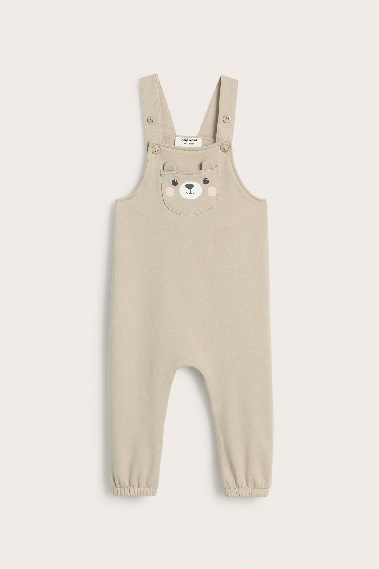 Widok z przodu: Beżowe ogrodniczki niemowlęce z misiem i uszami na kieszeni, zapinane na guziki.