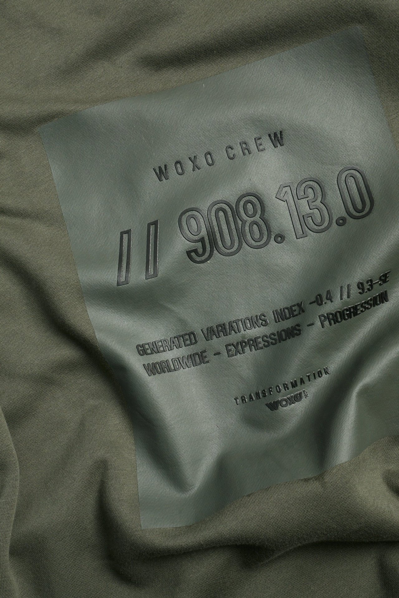 Zbliżenie zielonej bluzy z ciemnozielonym nadrukiem graficznym z przodu.