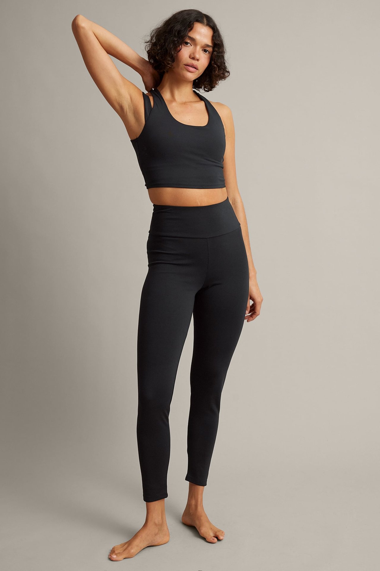 Framifrån, kvinna i svarta högmidjade leggings och svart magtopp.