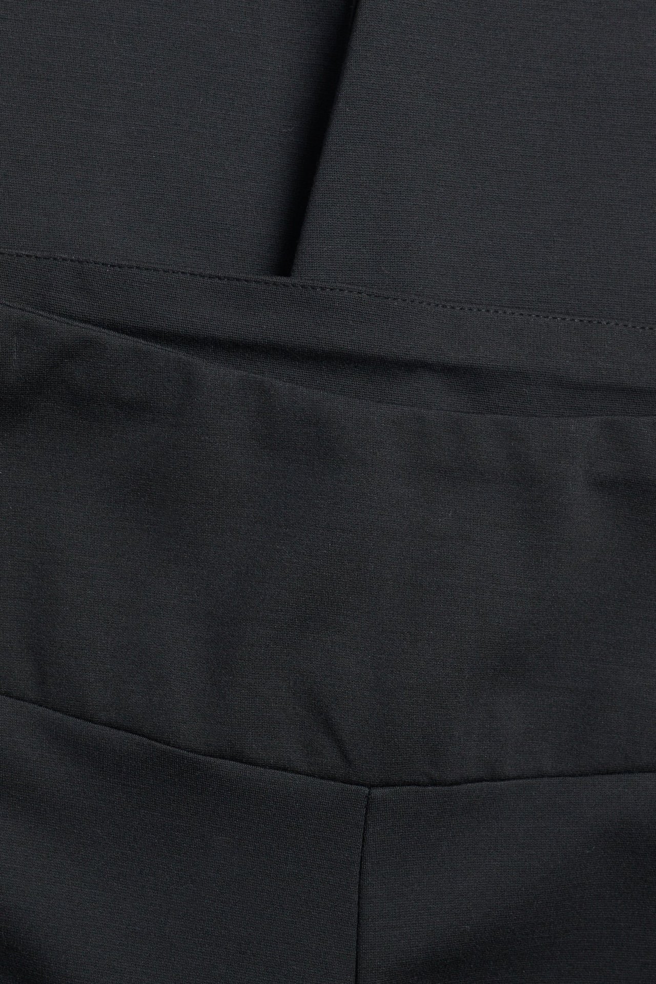 Närbild av svarta enfärgade högmidjade leggings med synliga sömmar på midjebandet och grenen.