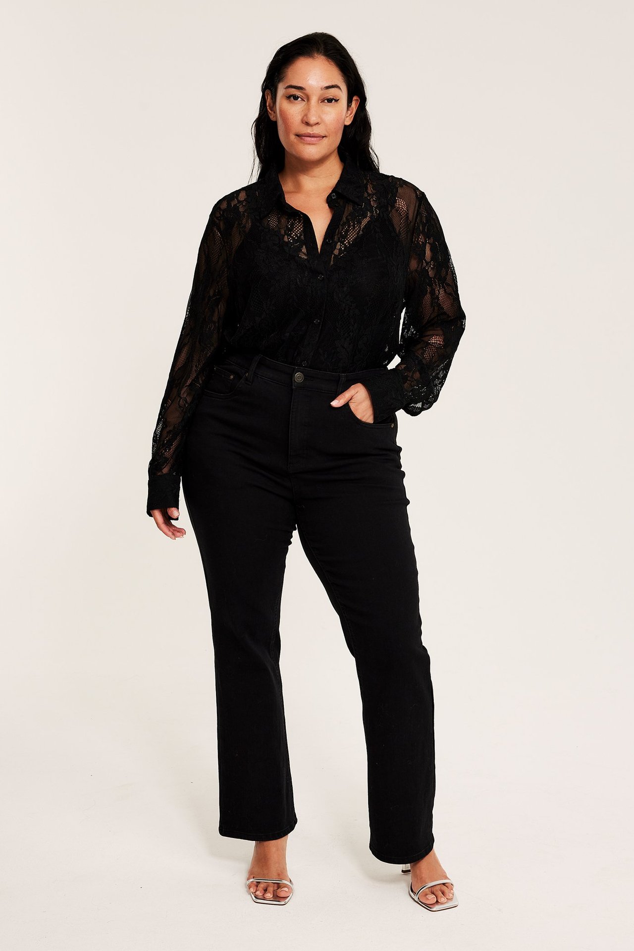 Svart spetskjorta med knäppning i enfärgad design, bärs av kvinna, framifrån.