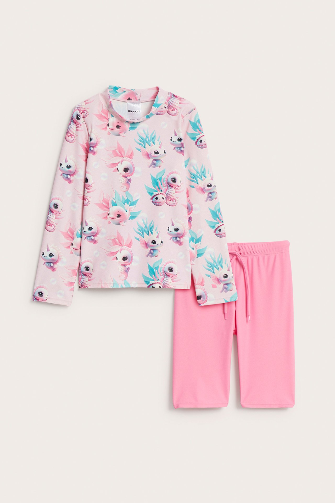 Edestä: lasten pinkki kuvioitu UV-setti, pitkähihainen paita ja yhteensopivat pinkit shortsit nyörivyötäröllä.