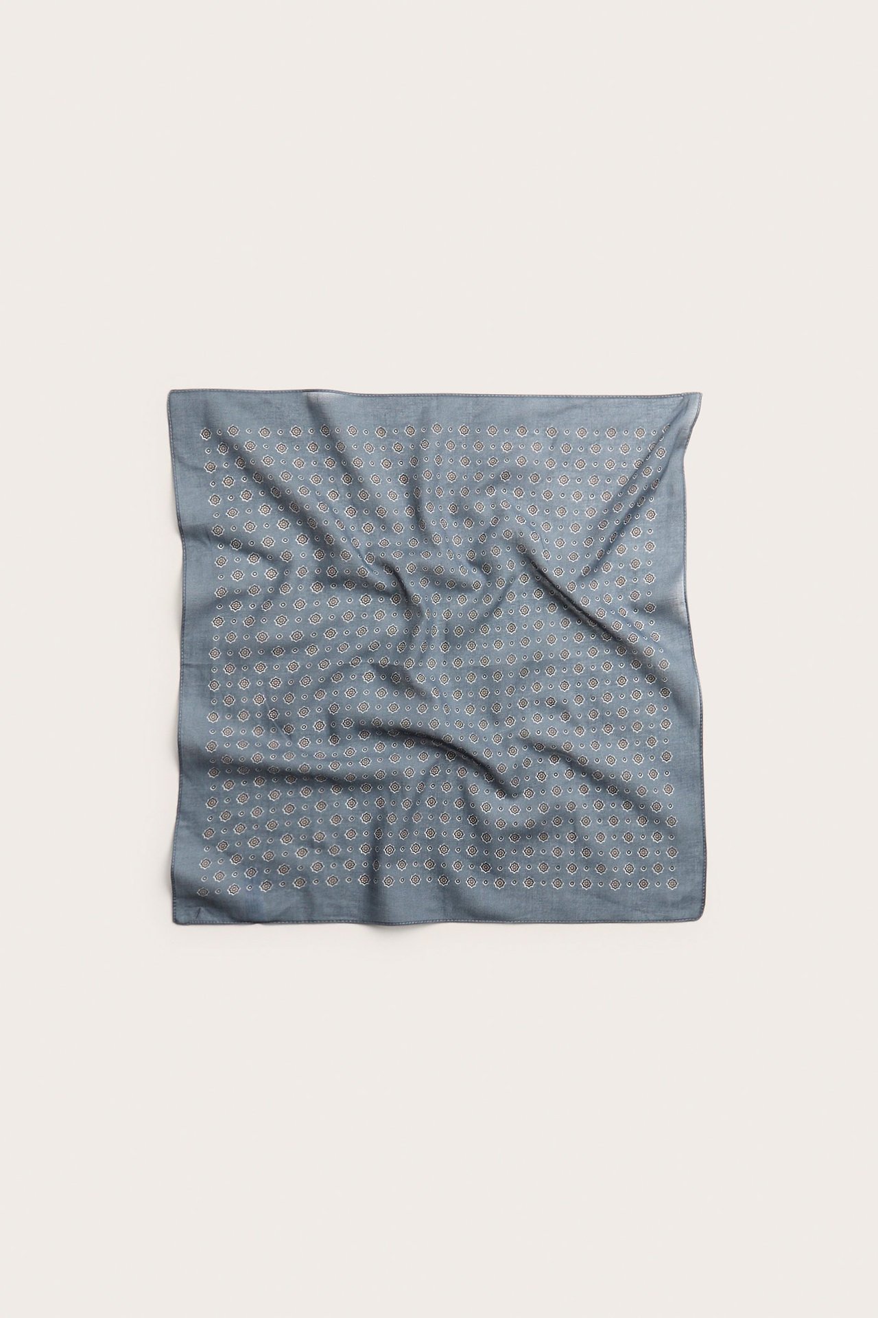 Widok z góry na kwadratowy, cienki niebieski bawełniany szalik z jasnym geometrycznym wzorem.