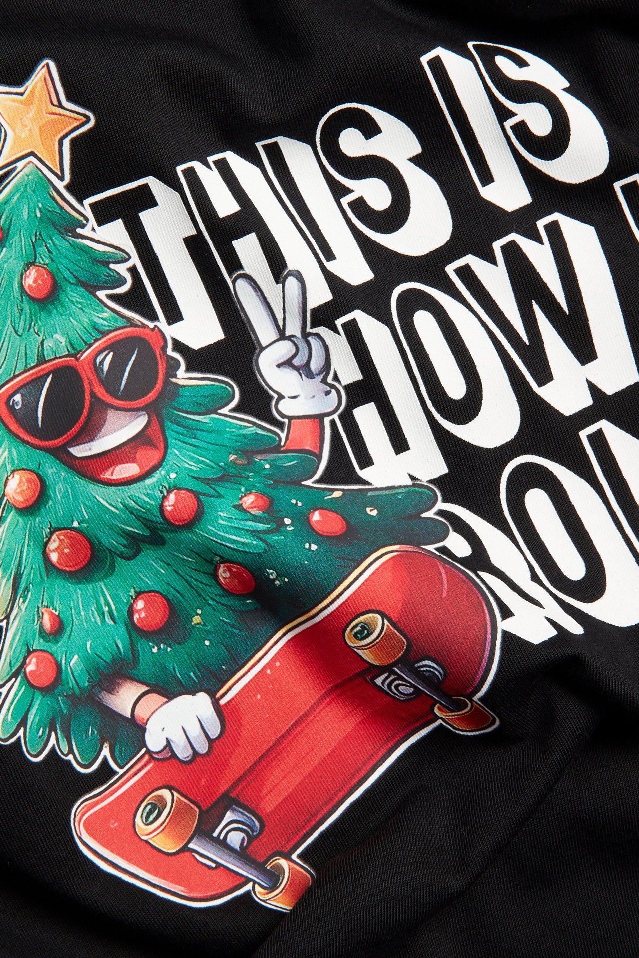 Zbliżenie czarnego, bawełnianego t-shirtu z długim rękawem z nadrukiem choinki, deskorolki i tekstu.