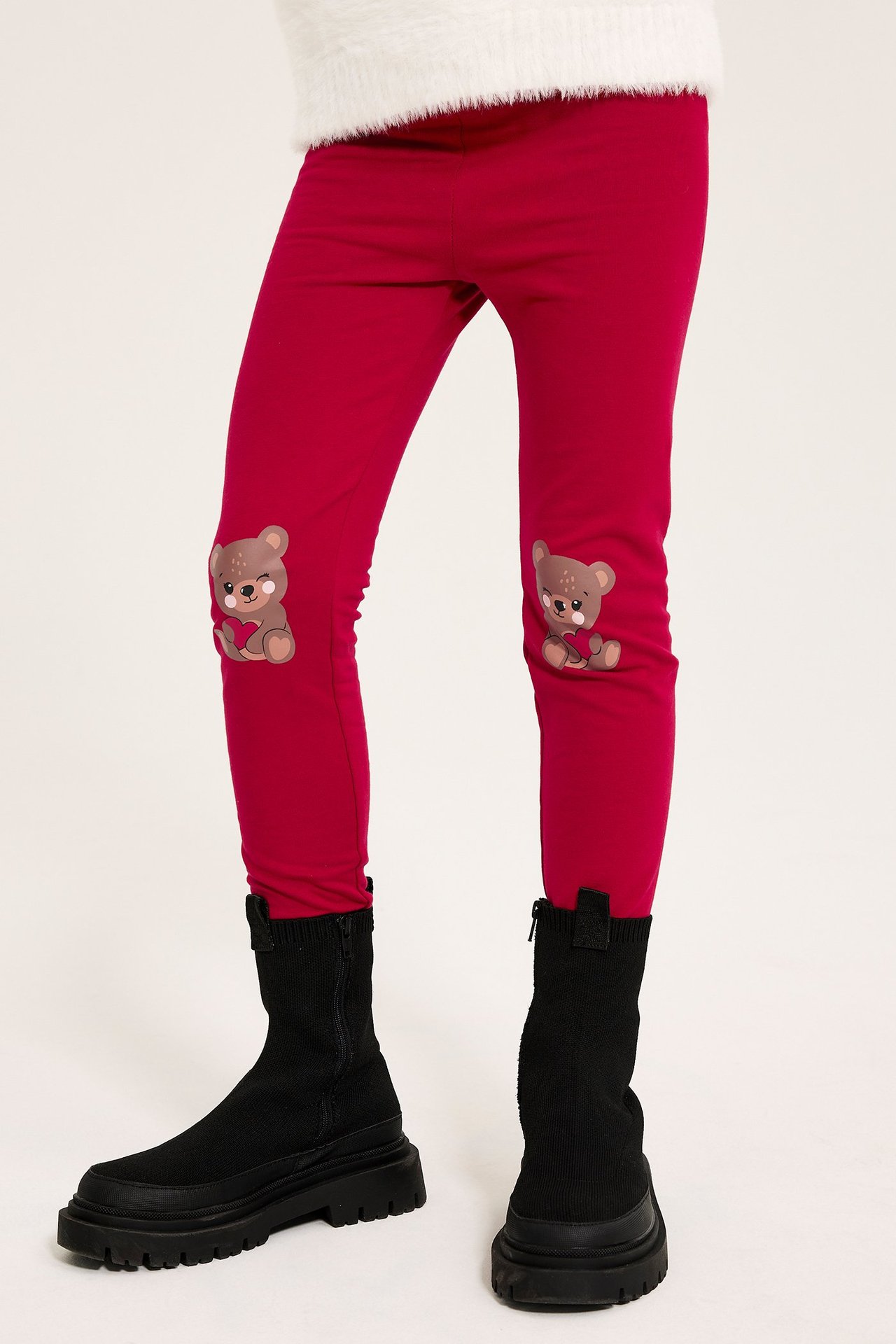 Røde leggings med bjørnapplikasjon på knærne, smal passform, svarte støvler.