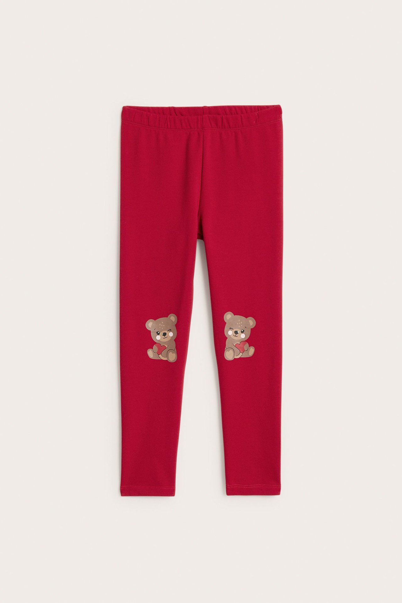 Widok z przodu: czerwone legginsy dziecięce z czesanym wnętrzem i uroczymi aplikacjami misia na kolanach.
