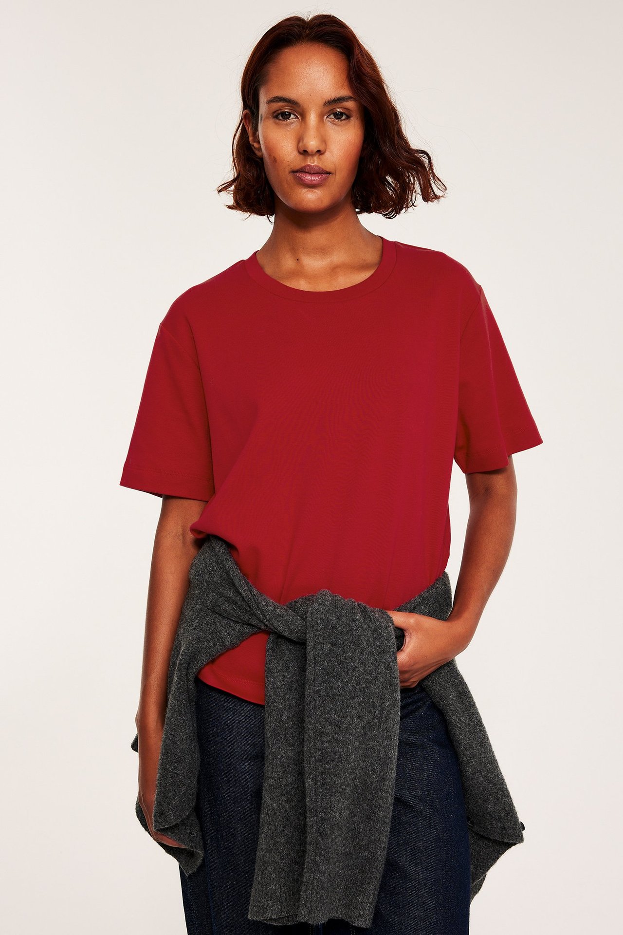 Rød oversized T-skjorte i interlock, over svarte bukser, frontvisning.