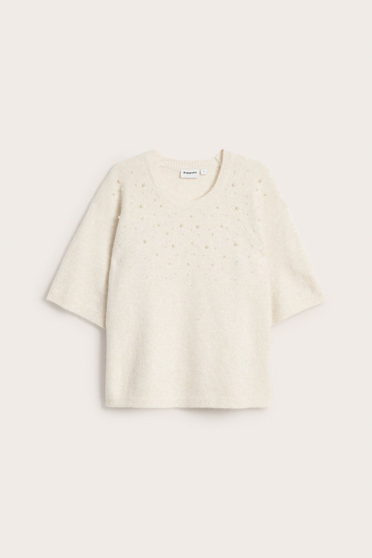Framsida av ljusbeige kortärmad stickad tröja med utspridda pärldetaljer.