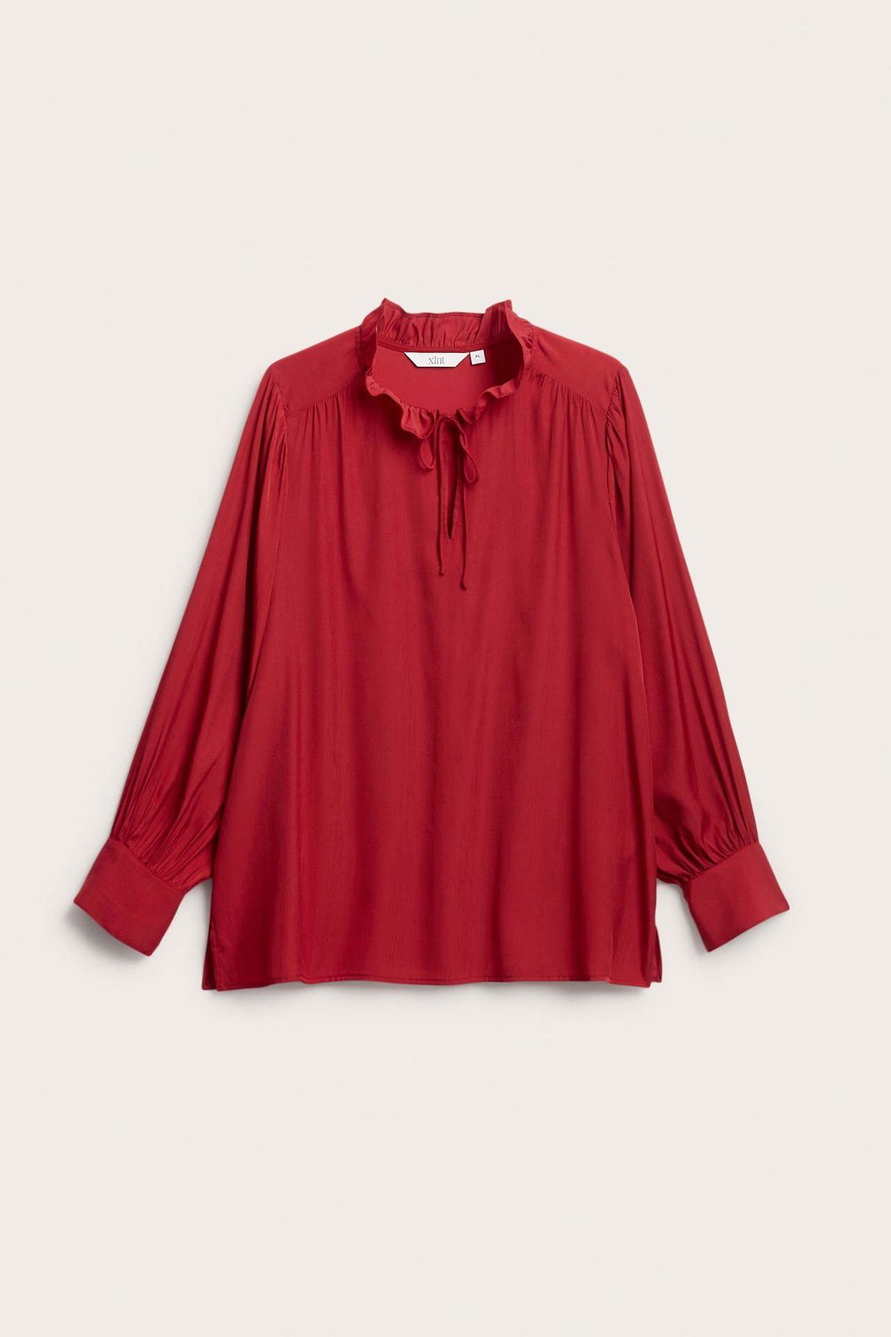 Widok z przodu: Czerwona bluzka z długim rękawem, falbankowym dekoltem i wiązaniami przy szyi i mankietach.