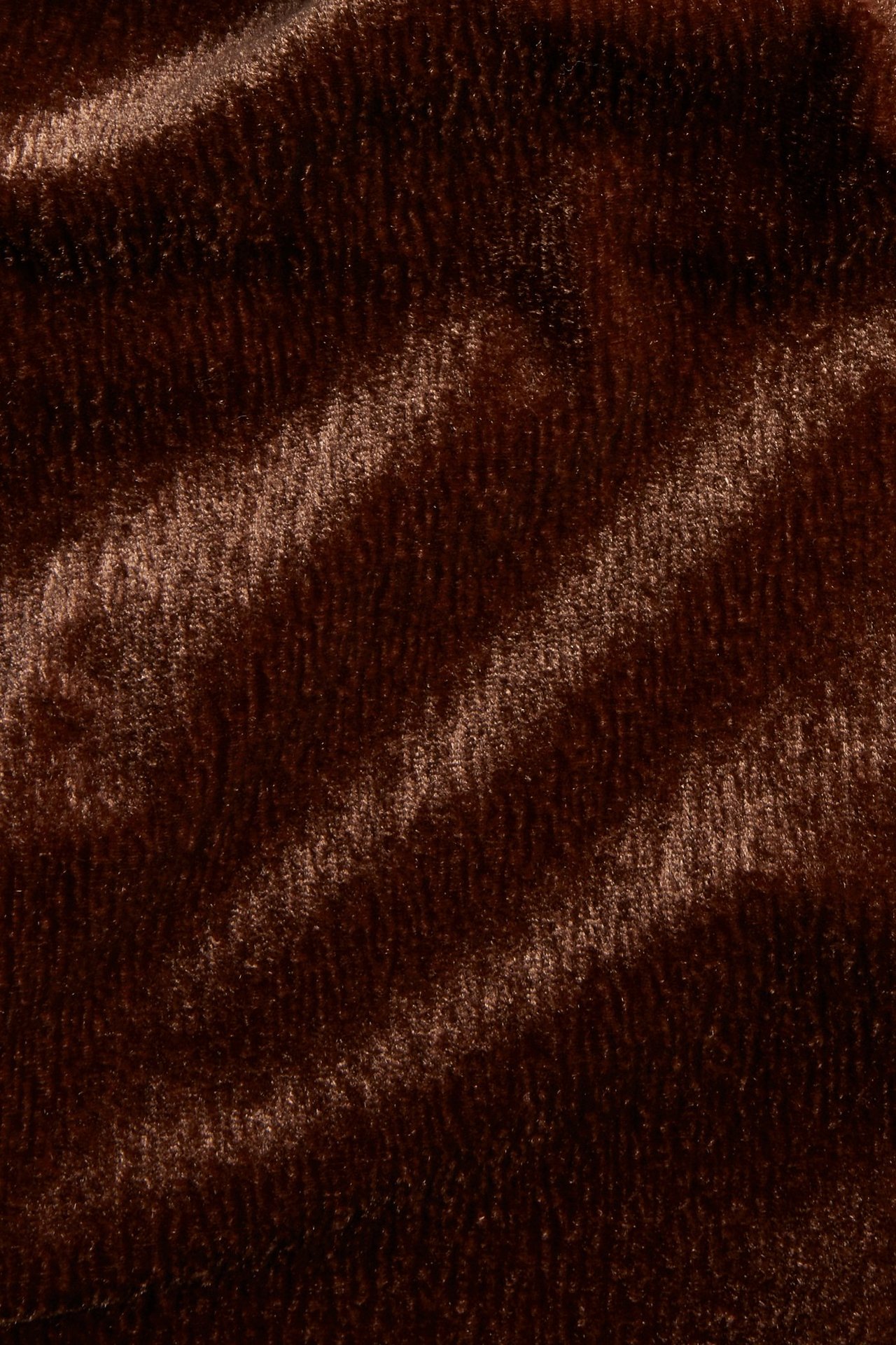Zbliżenie na brązowy strukturalny aksamitny materiał dżersejowy na spodnie, ukazujące jednolitą teksturę.