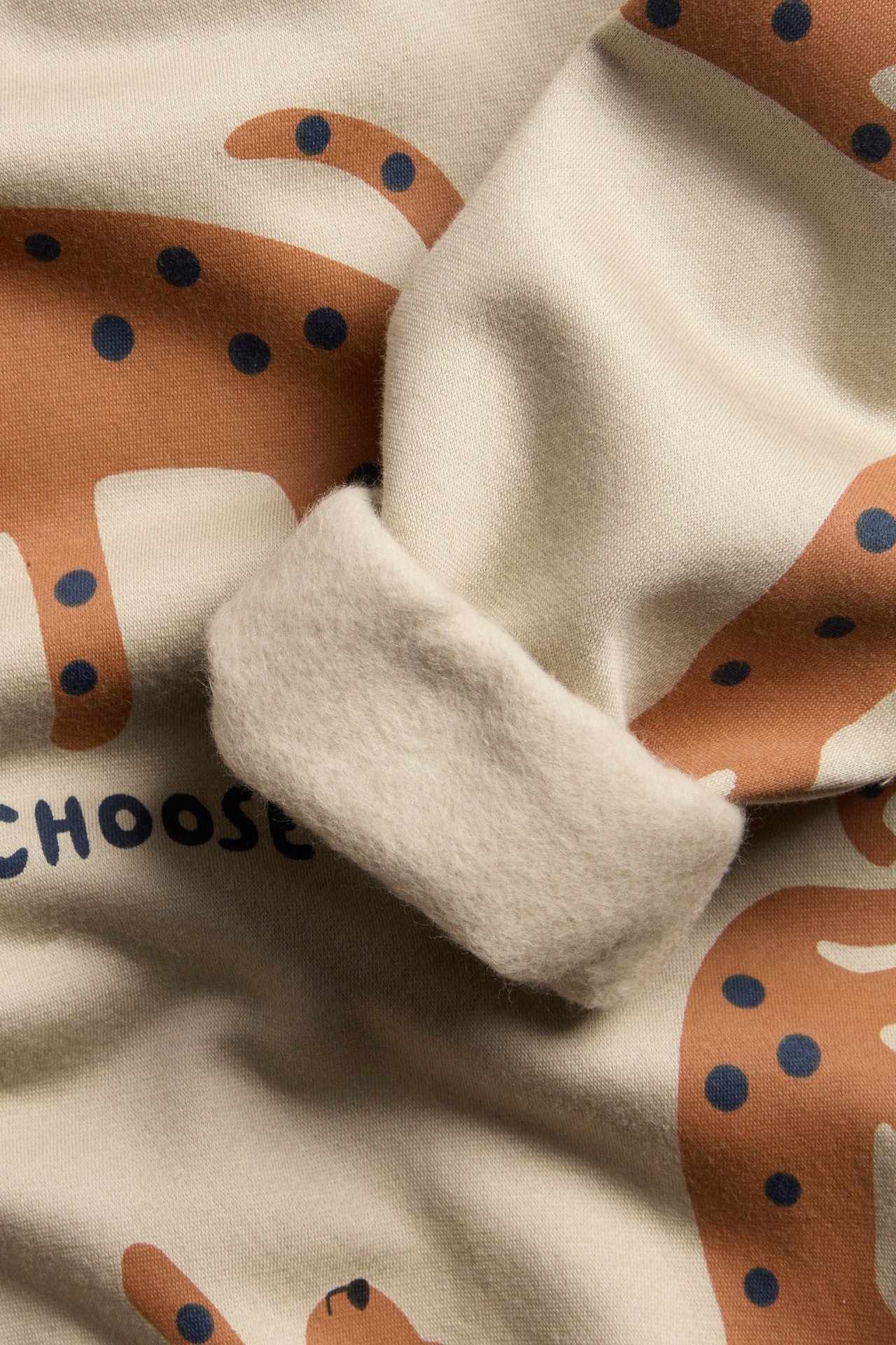 Beige-kuvioitu huppari printillä, kaula-aukko, mansetit ja helma, etualanäkymä.