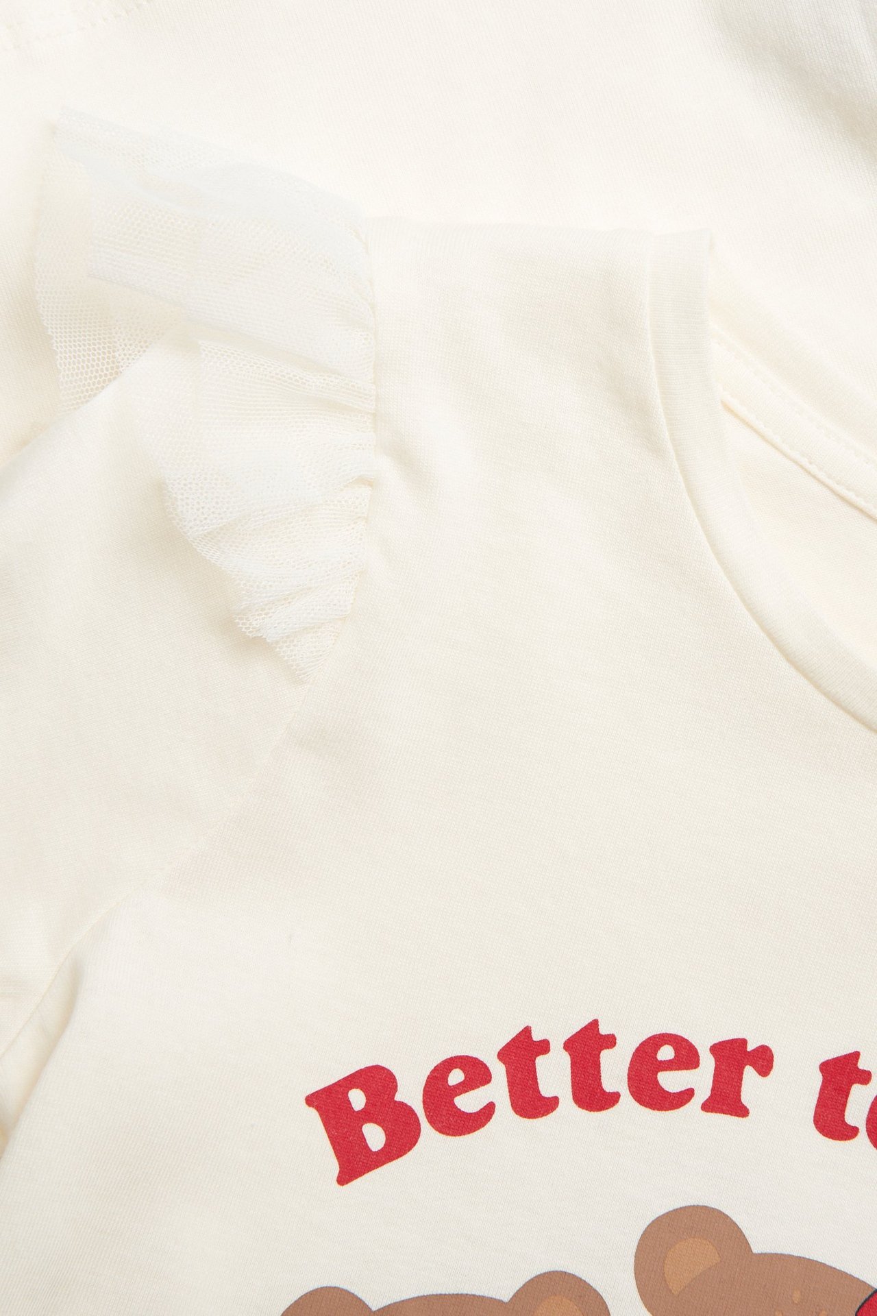 Ecru bluzka dziecięca, długi rękaw, bawełna, falbanki mesh, czerwony nadruk misia. Zbliżenie przód.