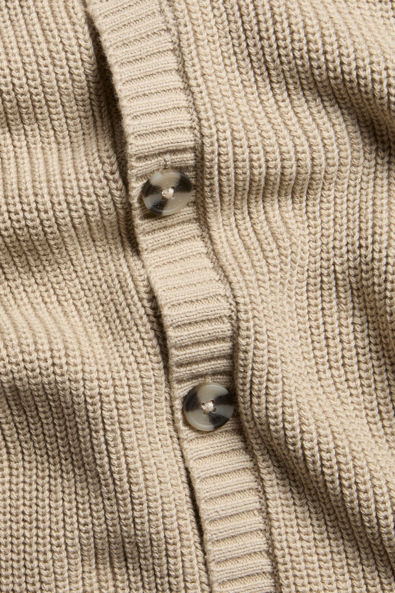 Beige stickad baby jumpsuit med knappar fram, enfärgad, ullblandning, nära vy.