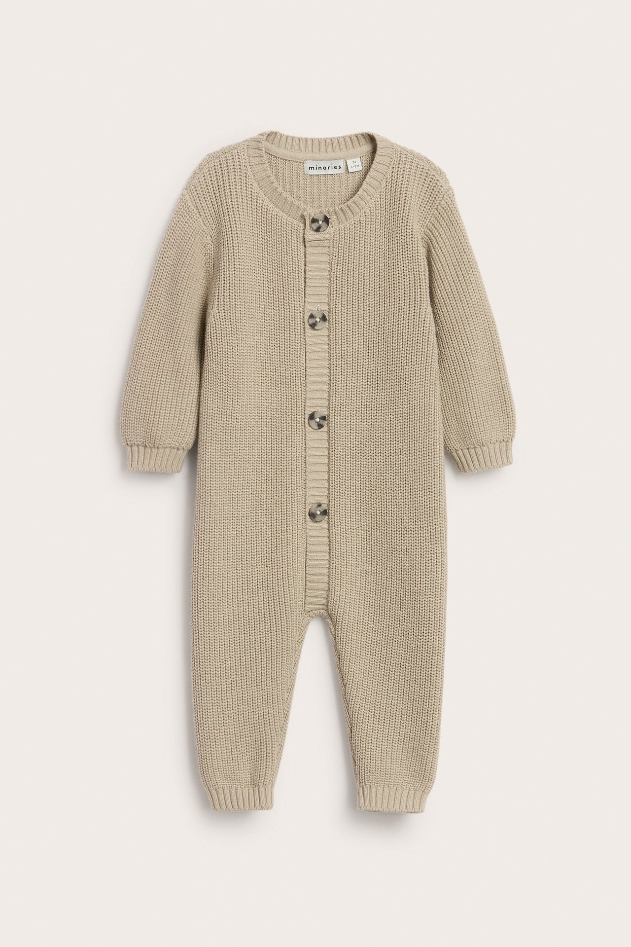Beige stickad baby jumpsuit med knappar fram, långärmad och enfärgad.