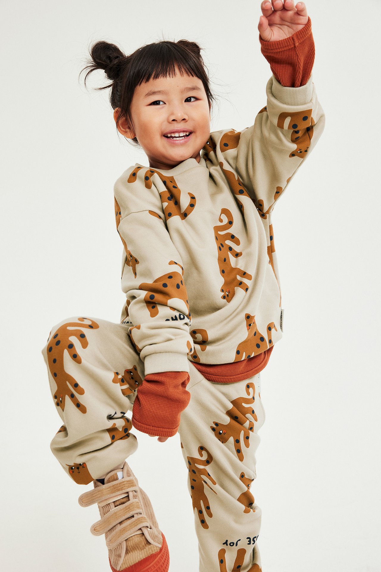 Dziewczynka w beżowych dżinsach z nadrukiem zwierząt, kieszeniami, regulowanym stanem, mankietami.