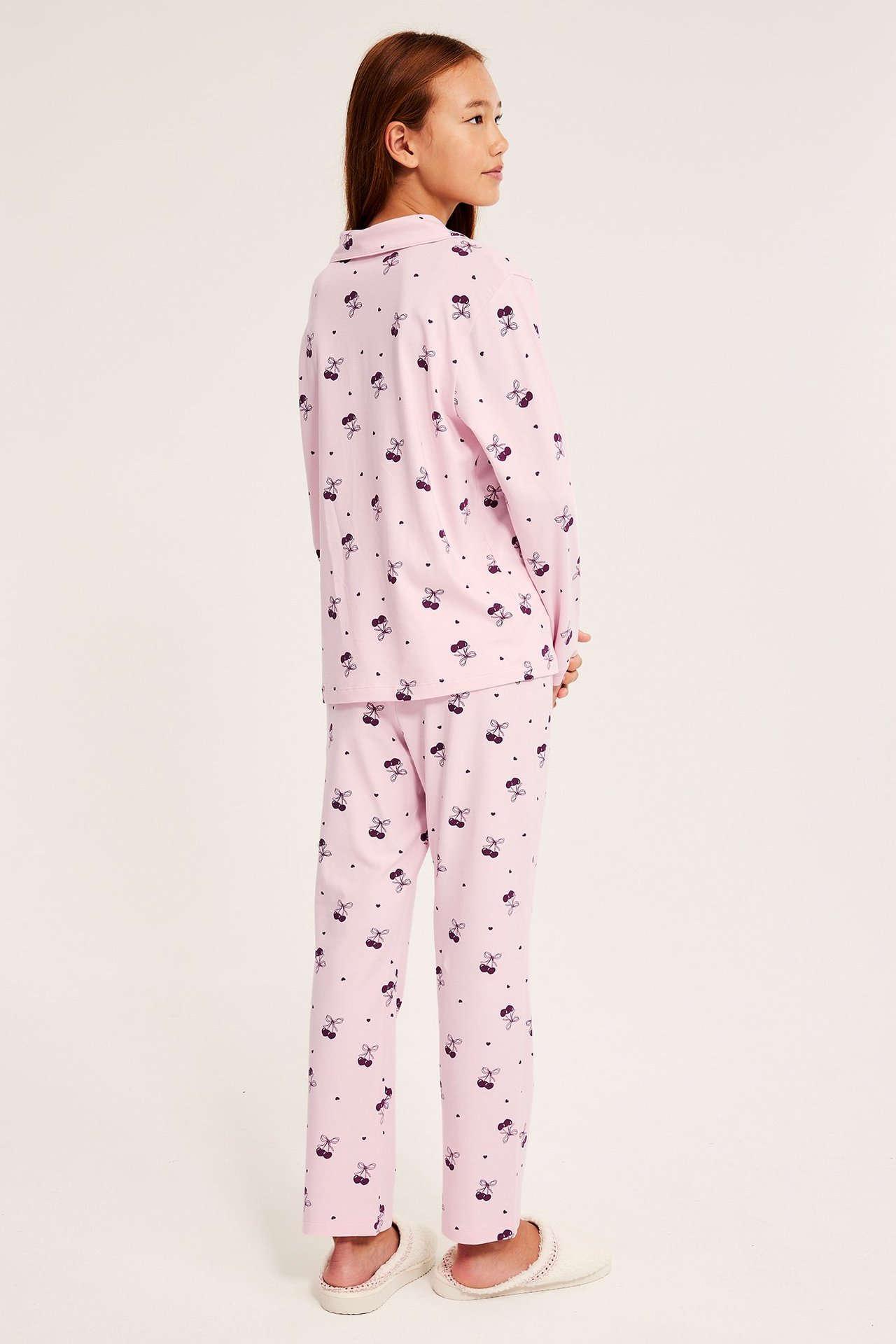 Pinkki trikoo-pijama, kuvassa nainen sivulta, kuvioinen perhonen.