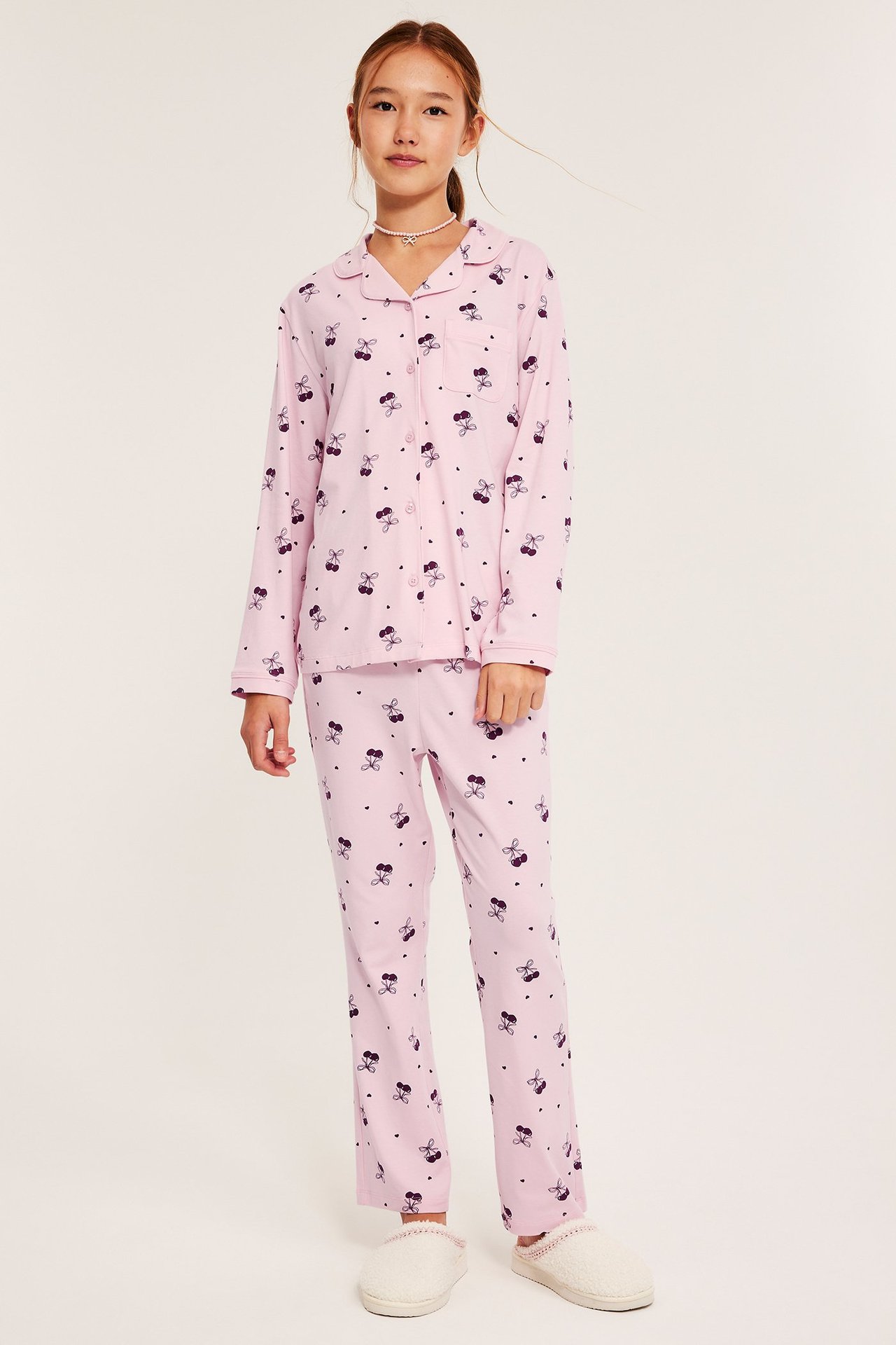 Tyttö vaaleanpunaisissa kuviollisissa puuvillapajama-soveluksissa, pitkähihainen yöpaita ja lahkeet.