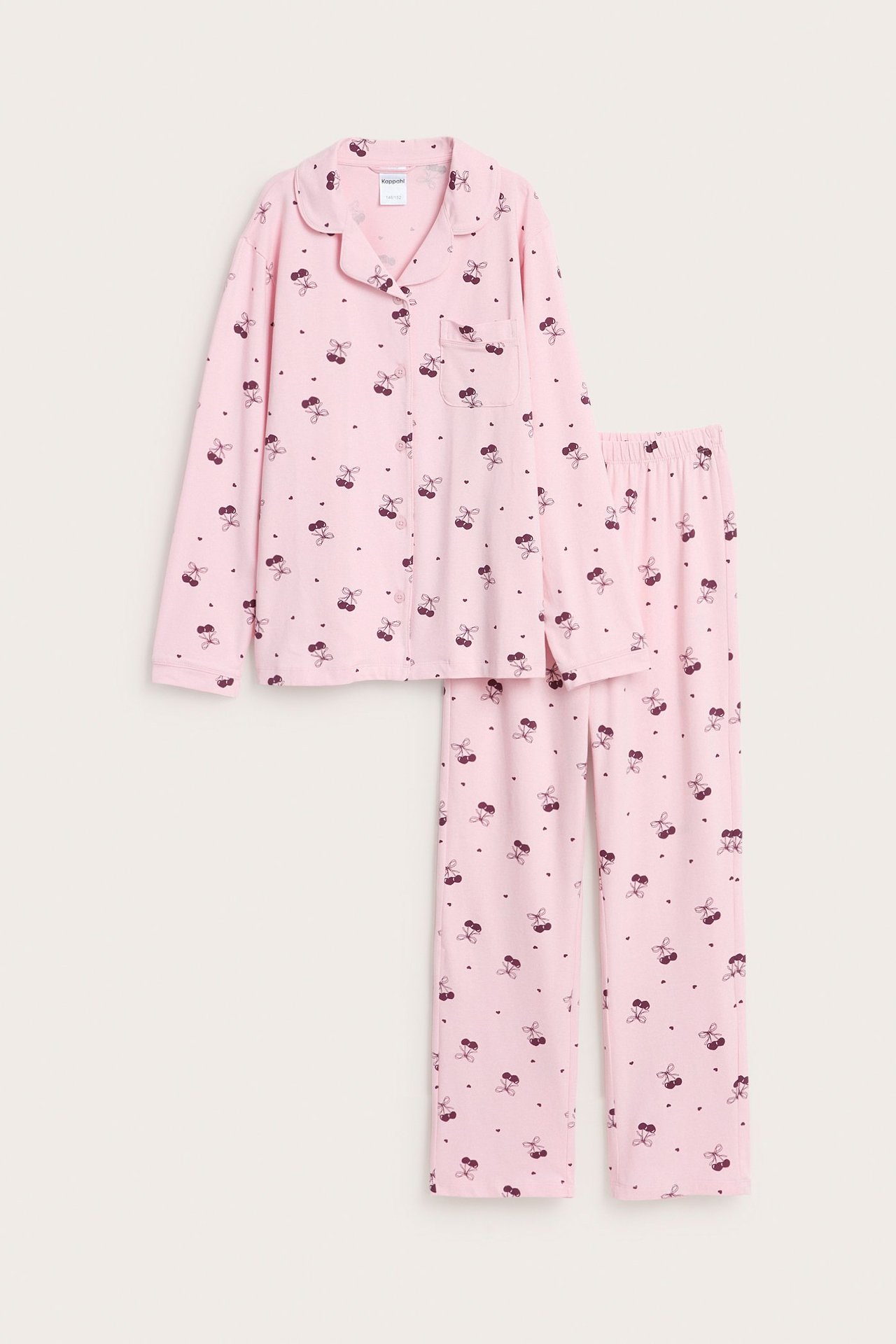 Vaaleanpunainen lastenpyjama trikookankaasta mustilla rusetillä, pitkähihainen yläosa ja housut.