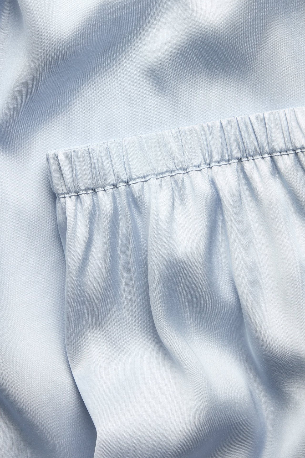 Nærbilde av lysblå satengpyjamasshorts med elastisk midje.