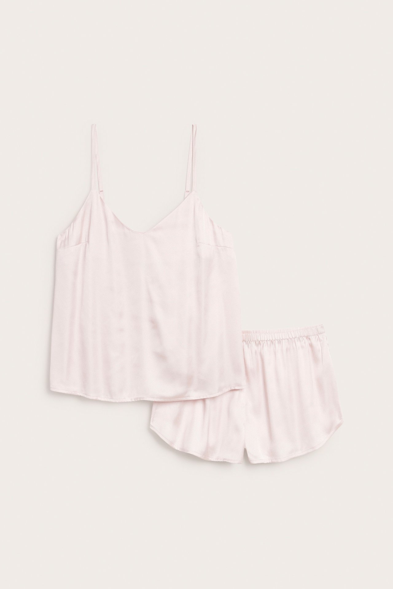 Frontbilde av et rosa satengpyjamasett, inkludert en camisoletopp med tynne stropper og matchende shorts.