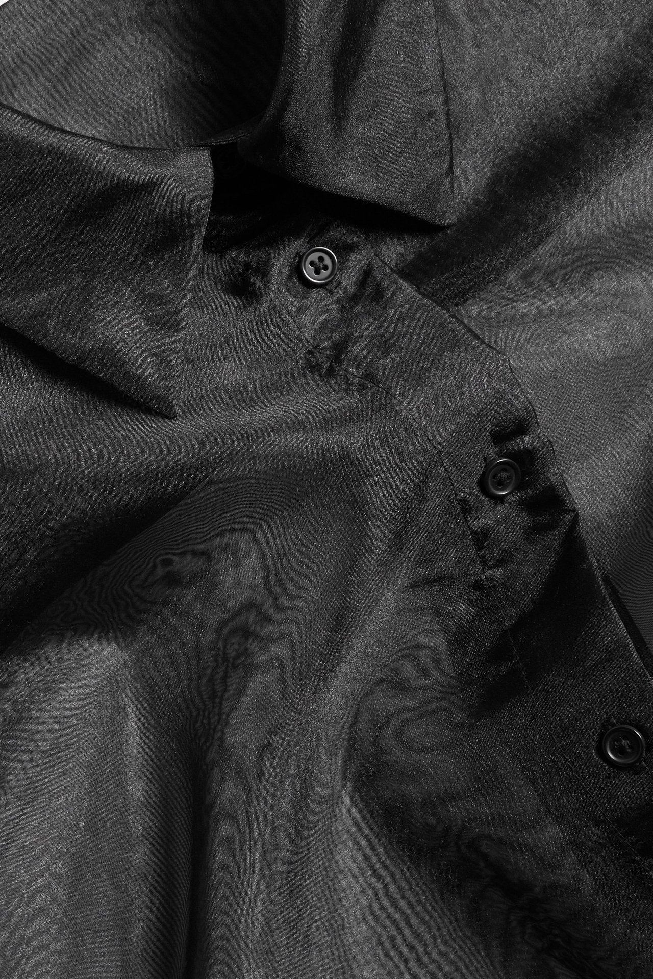 Zbliżenie czarnej, przezroczystej koszuli z organzy z kołnierzem i listwą guzikową.