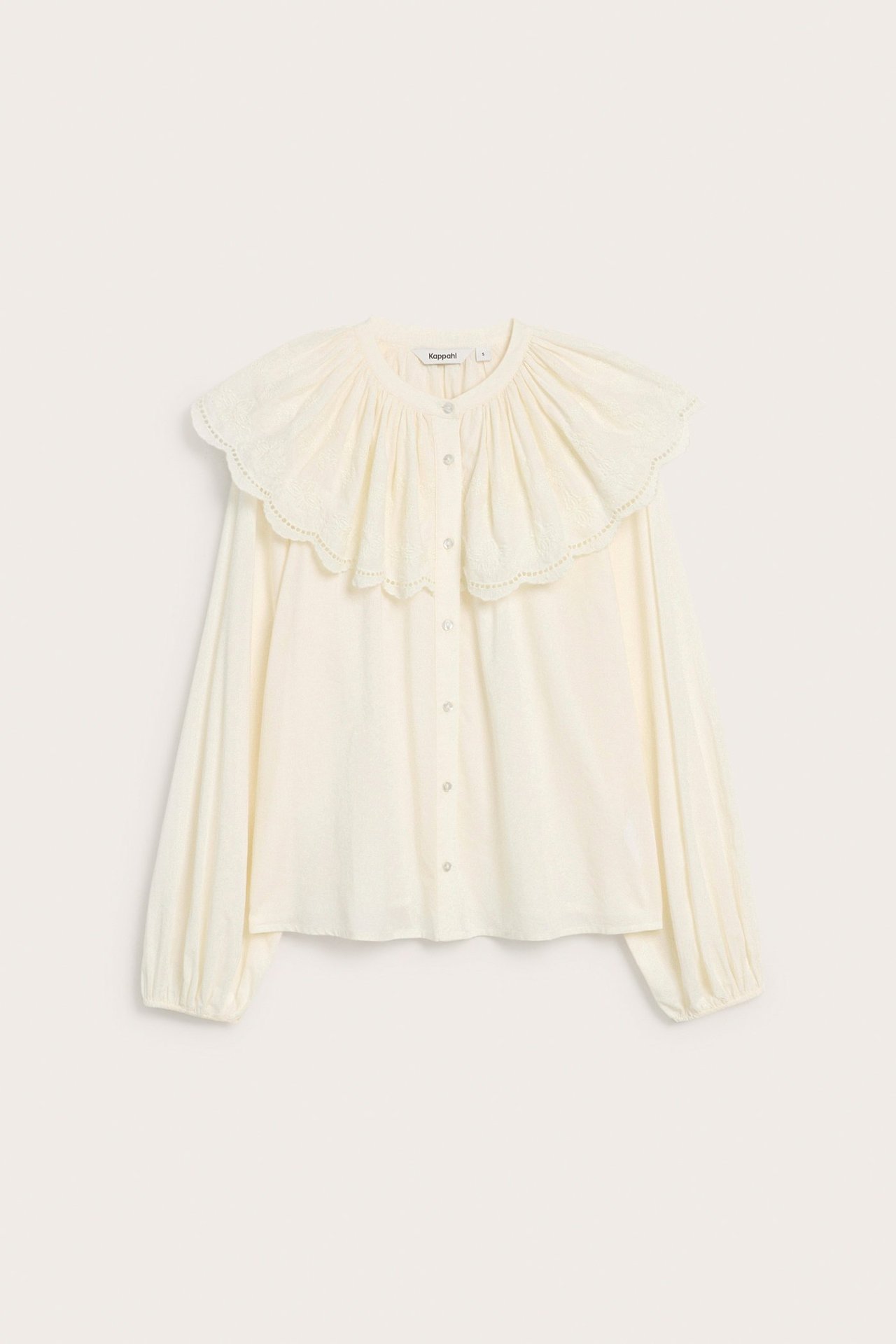 Edestä kuvattu luonnonvalkoinen puuvillapusero, jossa brodeerattu röyhelökaulus, napit ja joustavat hihansuut.