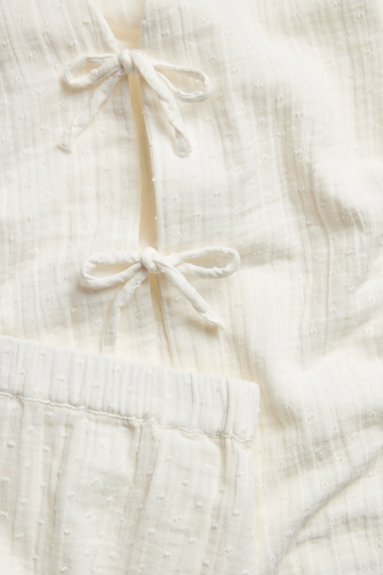 Zbliżenie beżowej piżamy z bawełny z wiązaną górą i elastyczną talią spodni.