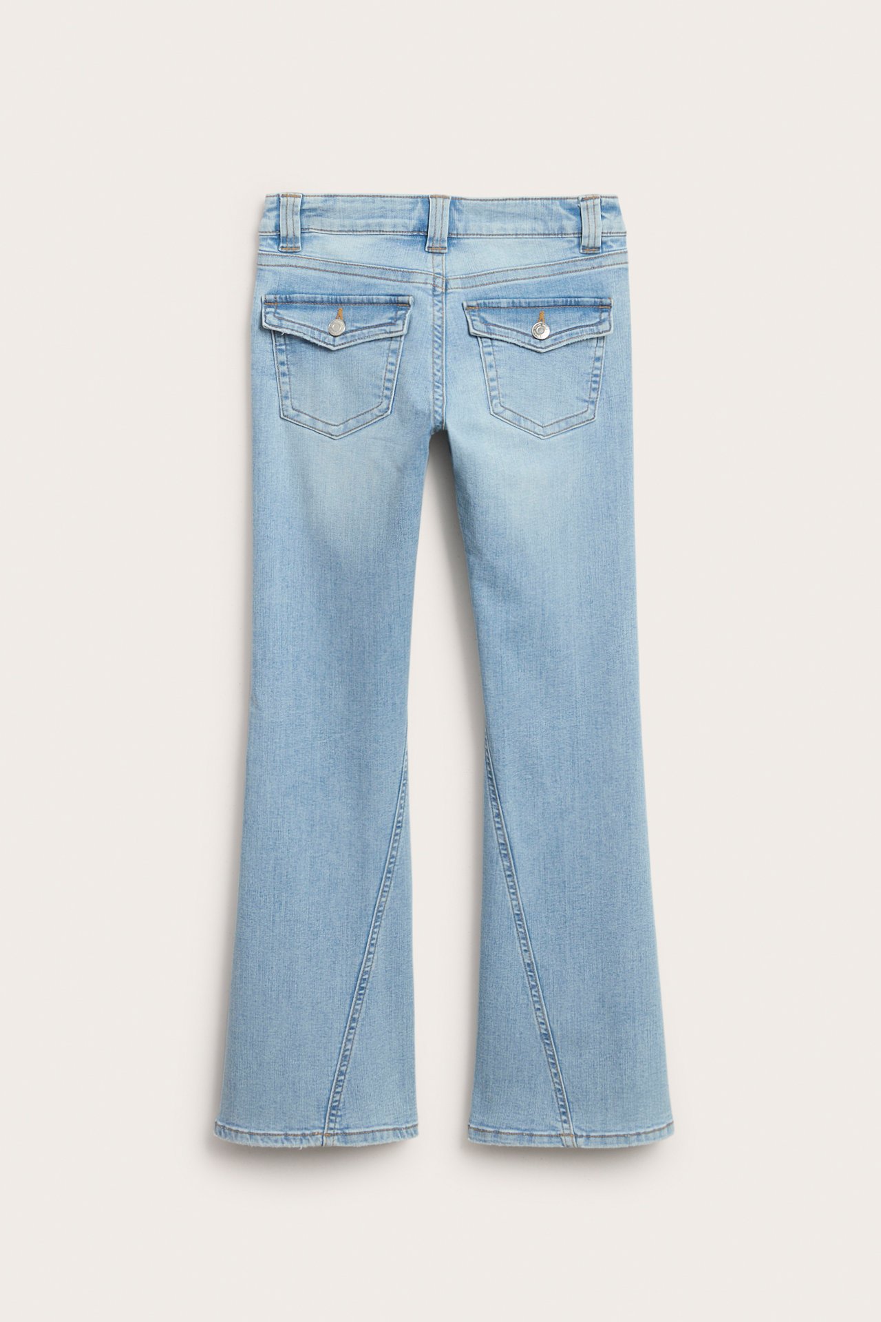 Vaaleat bootcut-farkut matalalla vyötäröllä, kierretyillä saumoilla ja napillisilla kaarevilla takataskuläpillä, takaa.