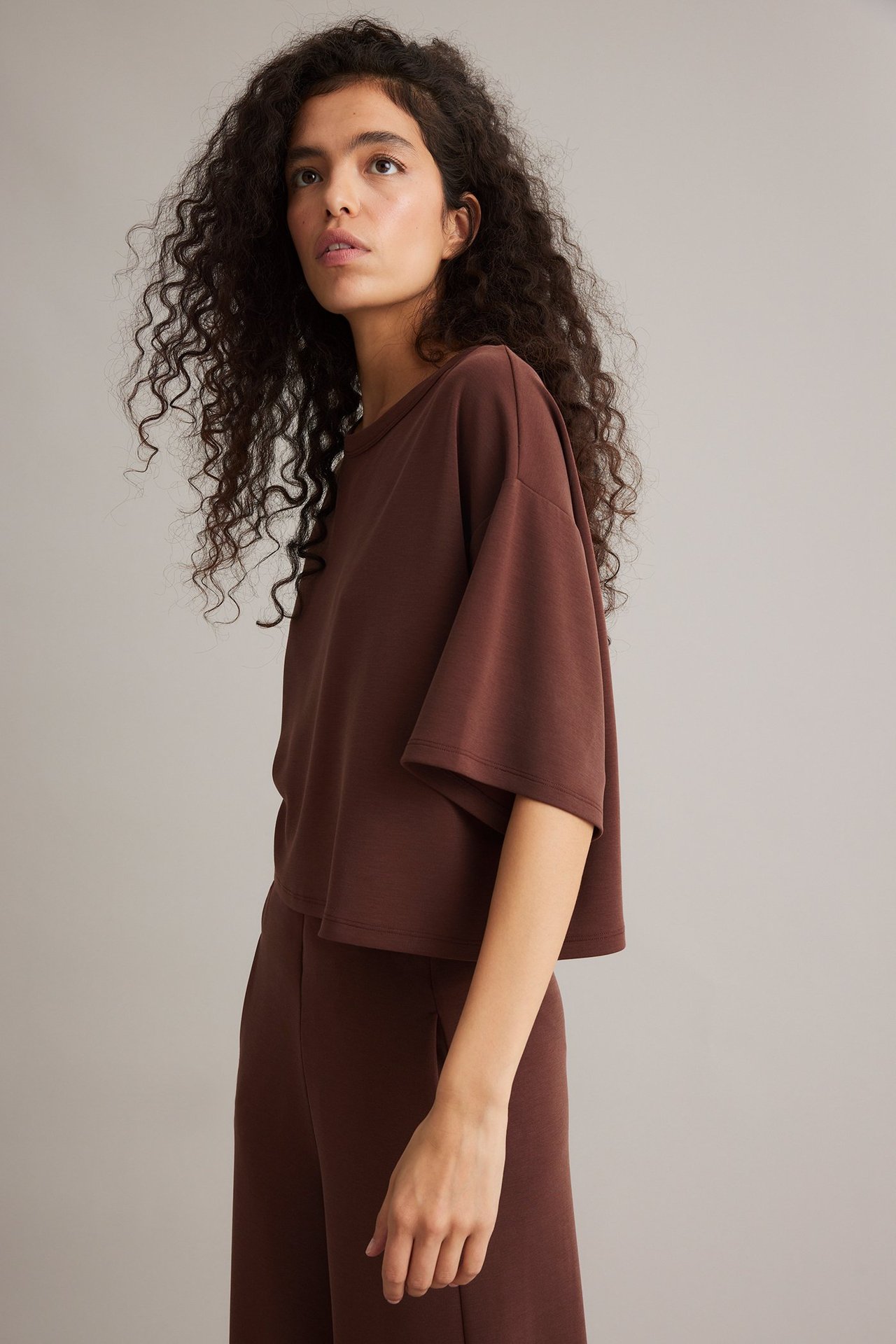 Sidovy av kvinna i vinröd, boxig T-shirt i modalblandning med vida ärmar och matchande byxor.