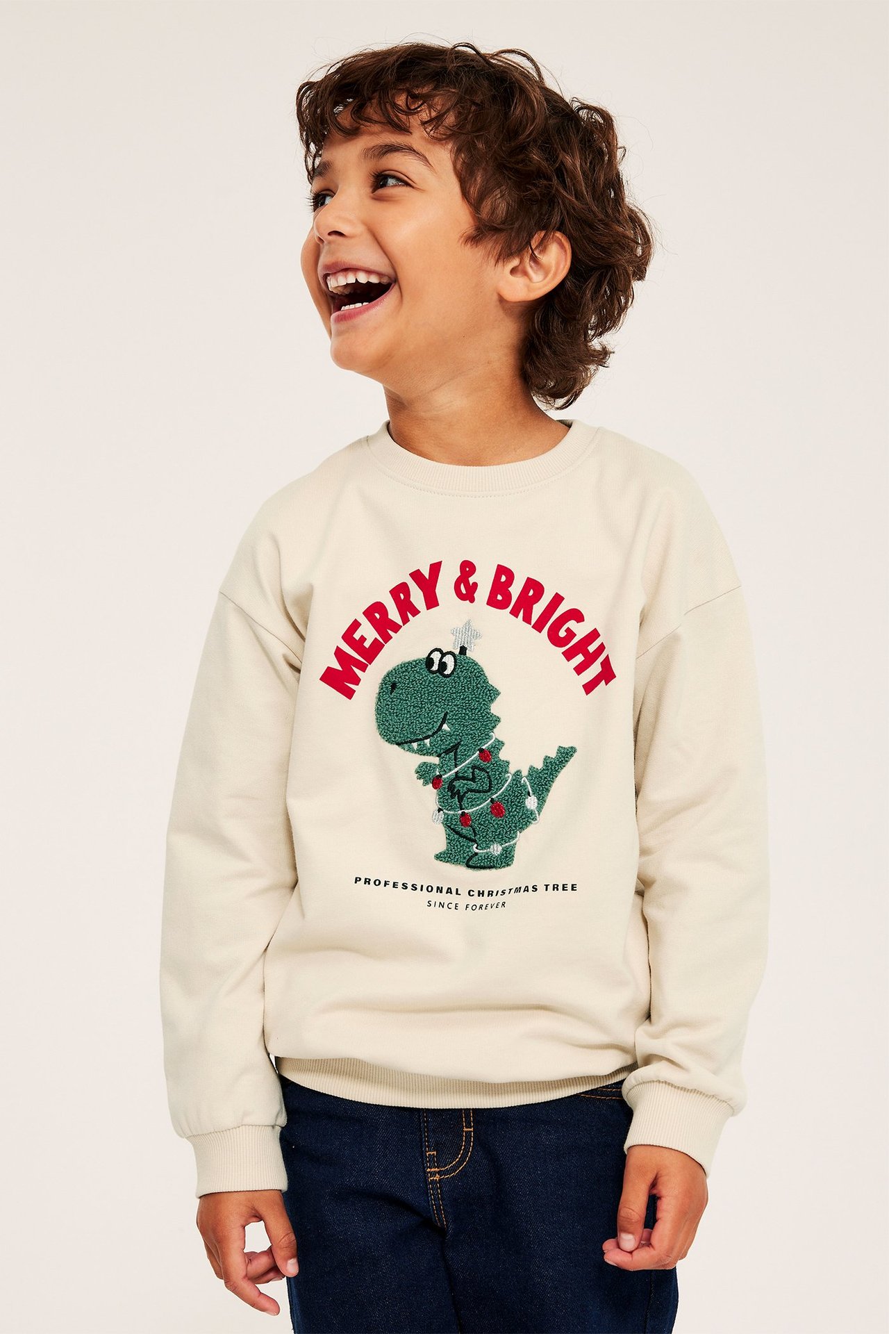 Sweter dla dzieci w beżowym kolorze z nadrukiem dinozaura i motywem świątecznym, ściągacze.