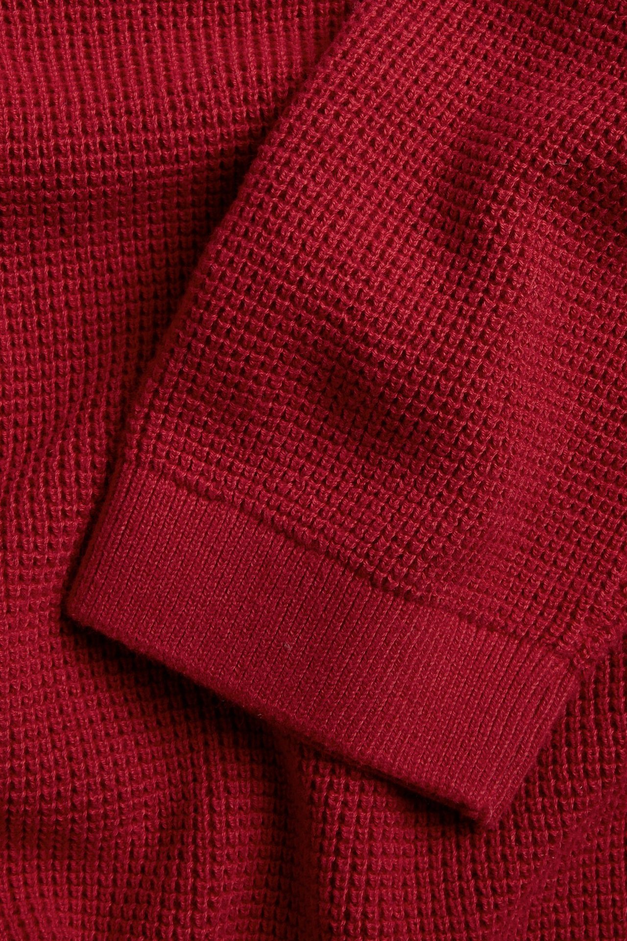 Zbliżenie czerwonego, dzianinowego swetra bawełnianego ze ściągaczem.