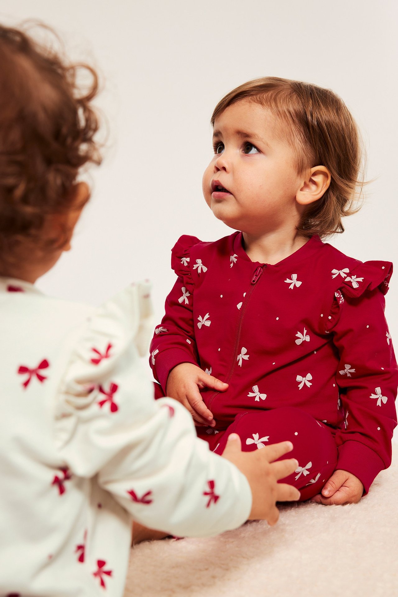 Rødt 2-pakk baby-onnie med toveis glidelås, volanger og blomsterprint.